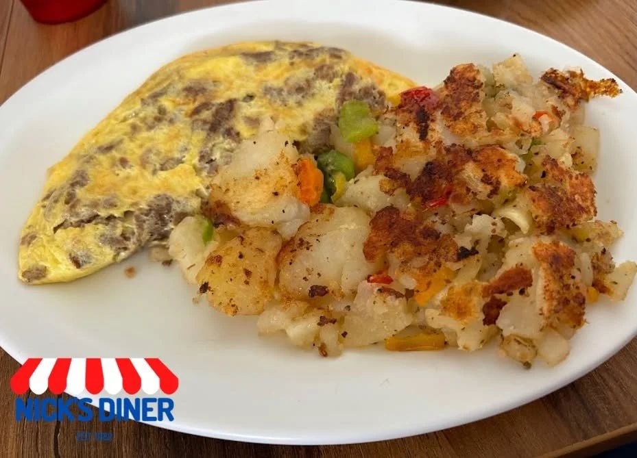 Omelette with sausage and a serving of roasted potatoes on a white plate from Nick's Diner.