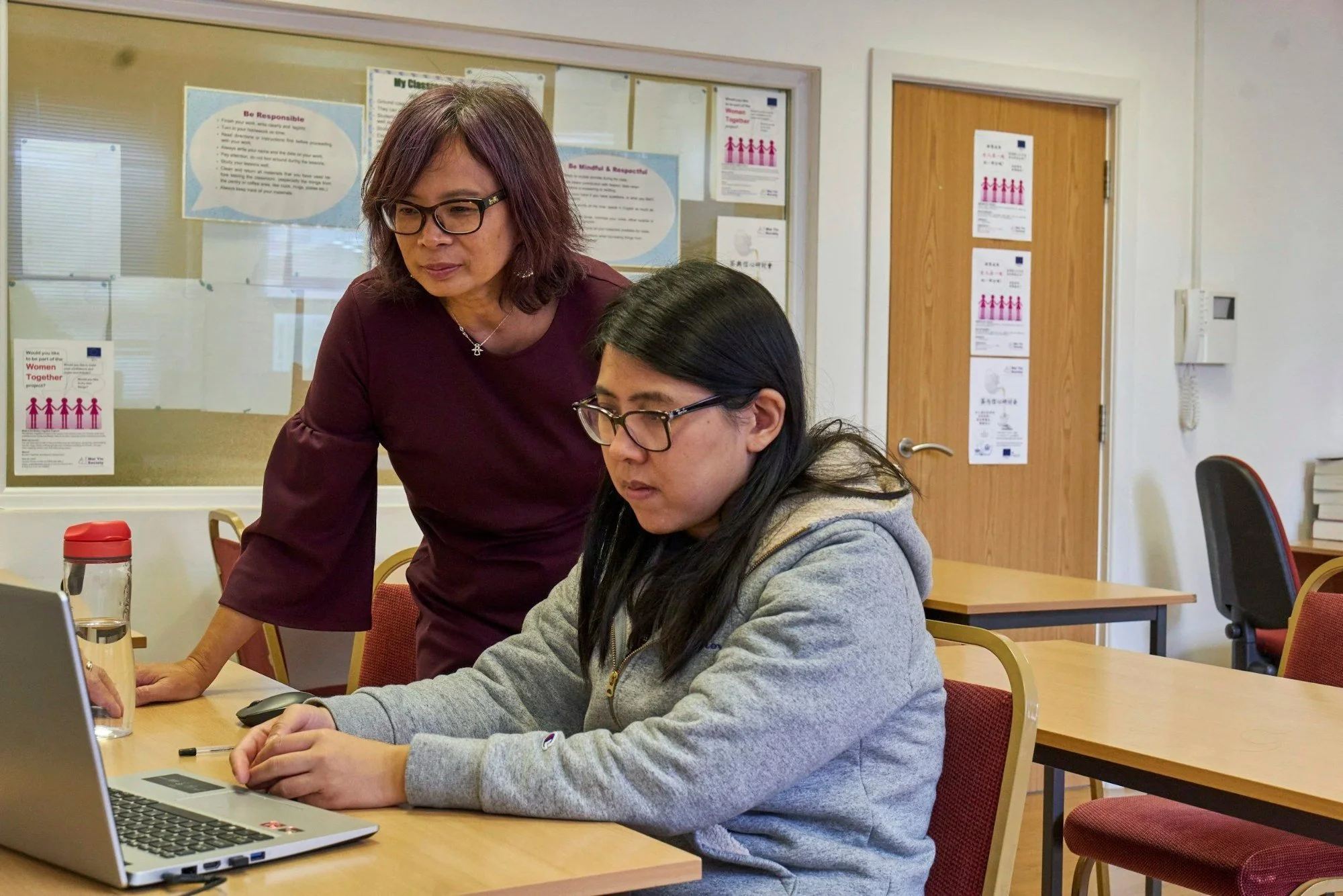 Educator working one-on-one with a student at a laptop