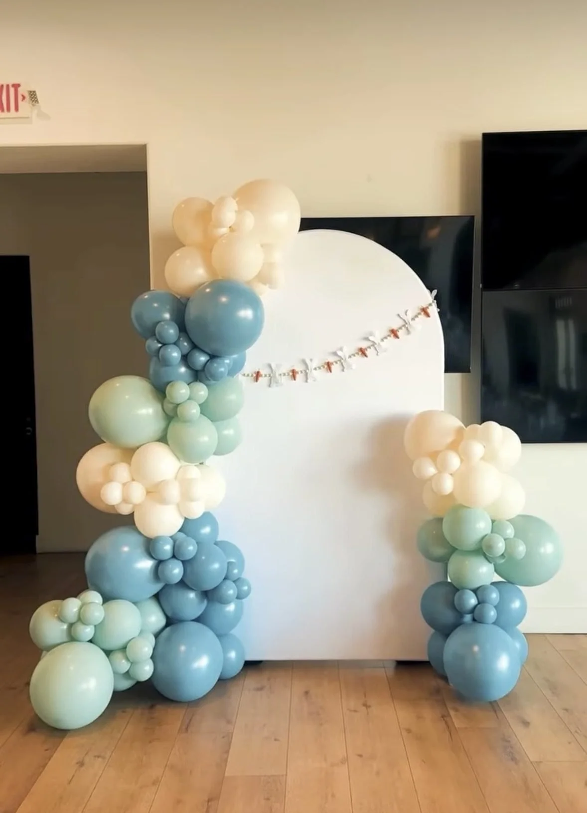 Blue and sage balloon columns framing a baby shower backdrop