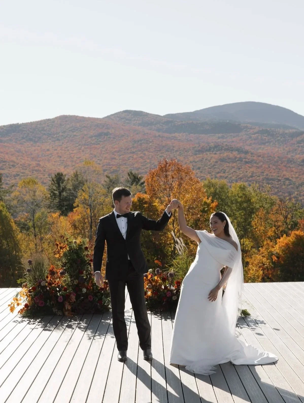 Bride and groom dancing on a deck overlooking colorful autumn mountains