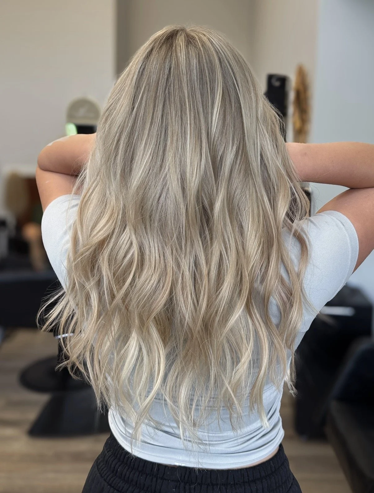 Back view of a woman with long, wavy silver-blonde hair and blended highlights