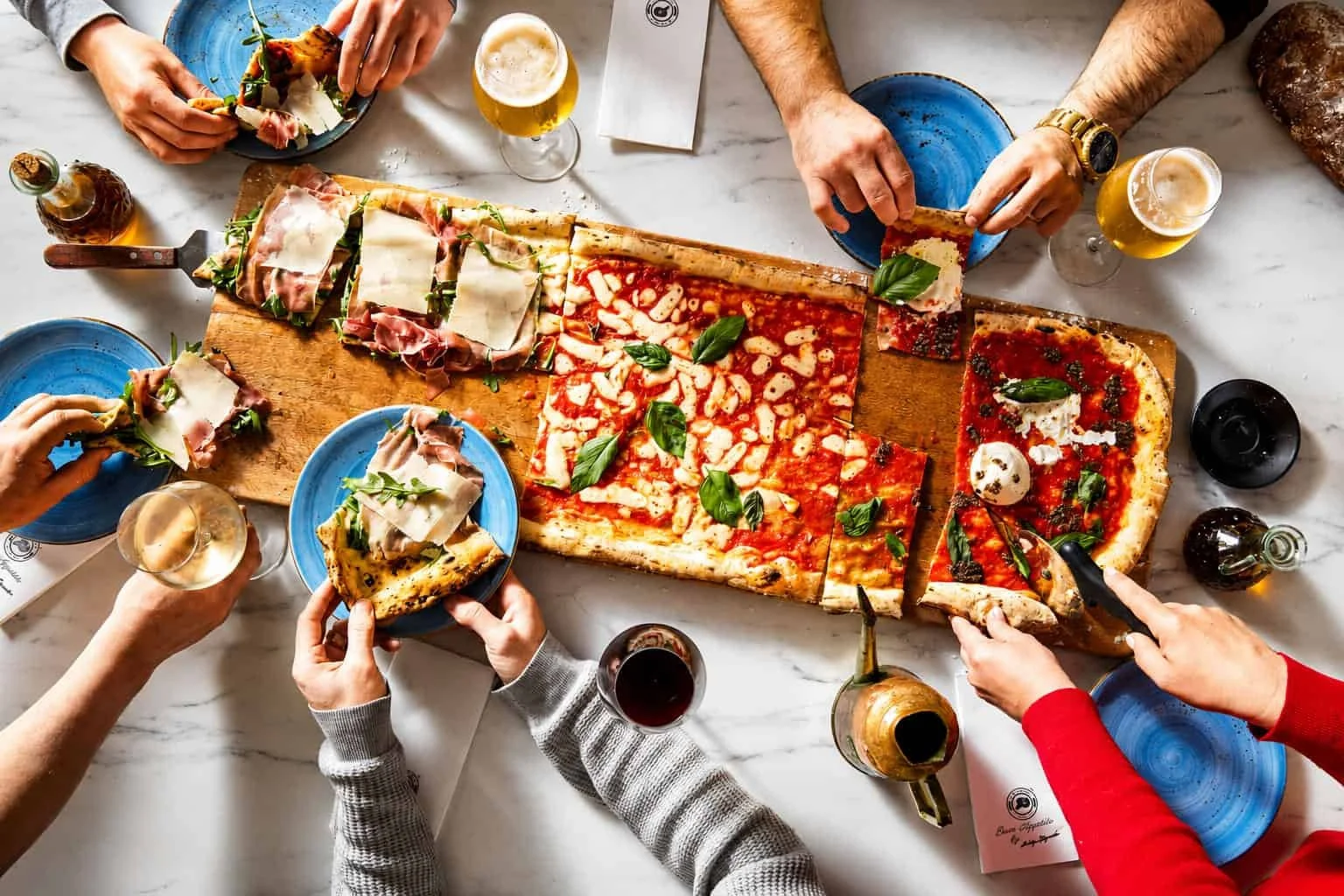 Persone che condividono una pizza e del vino in un ristorante.