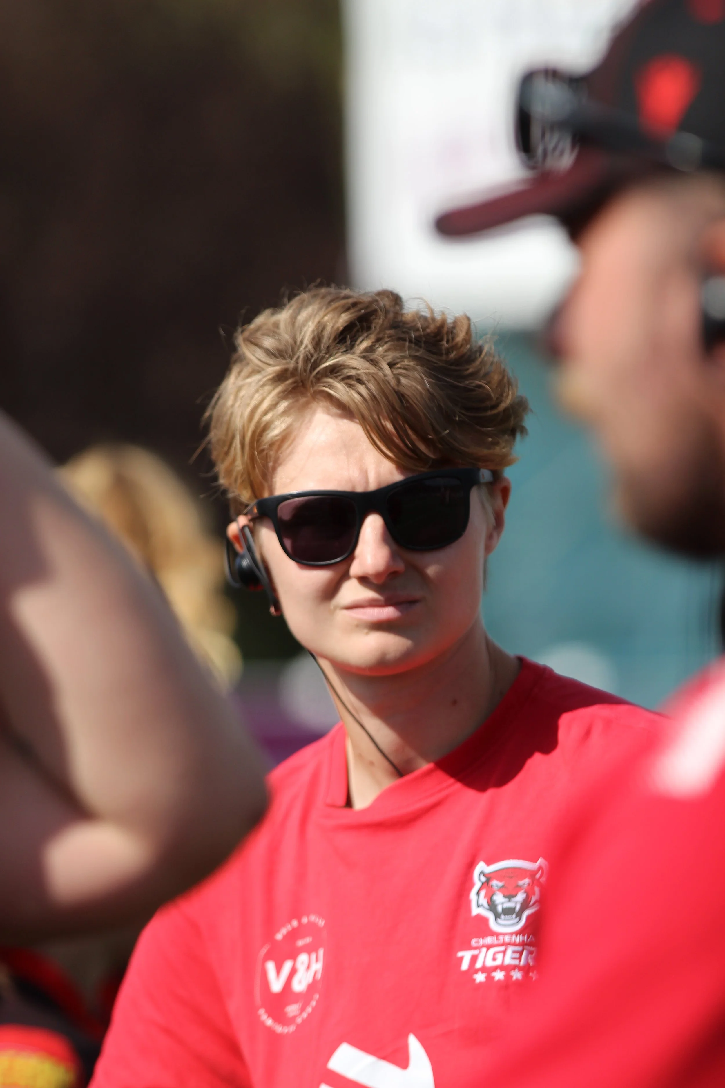 Amy Wigley, independent sports practitioner and coach, wearing coaching kit and headset on the touchline