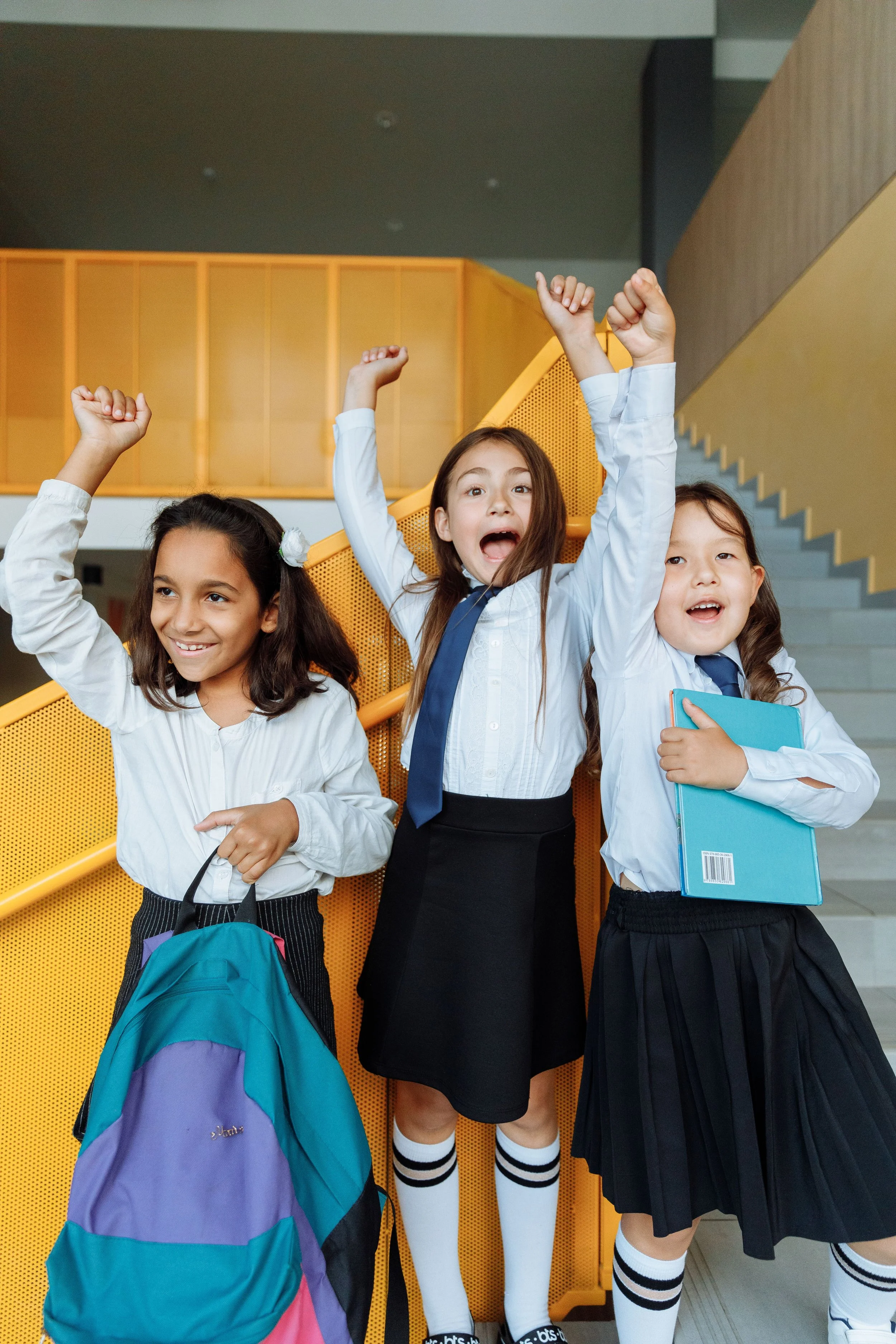 Three cheerful students smiling together, reflecting friendship, positivity and wellbeing in an educational setting.
