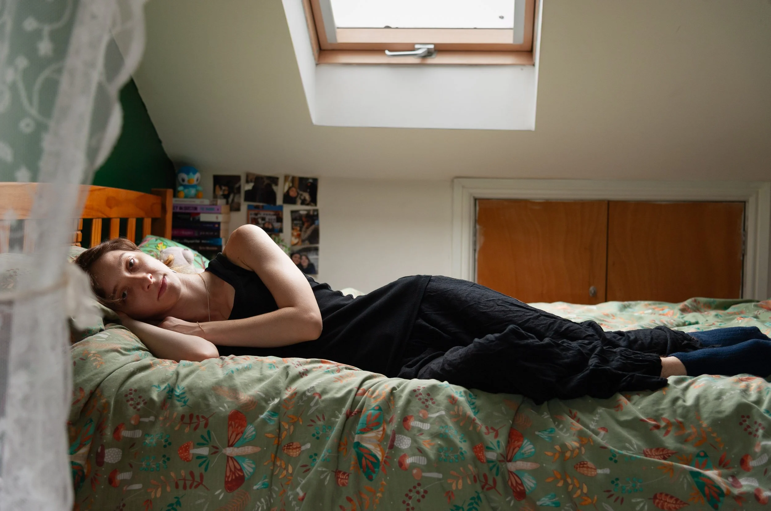 Woman lying on a bed in a cozy bedroom beneath a skylight