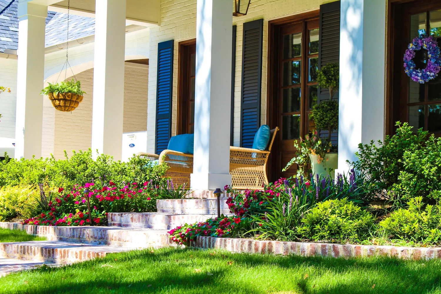 White-columned porch framed by flower beds and a manicured lawn at a Southlake home