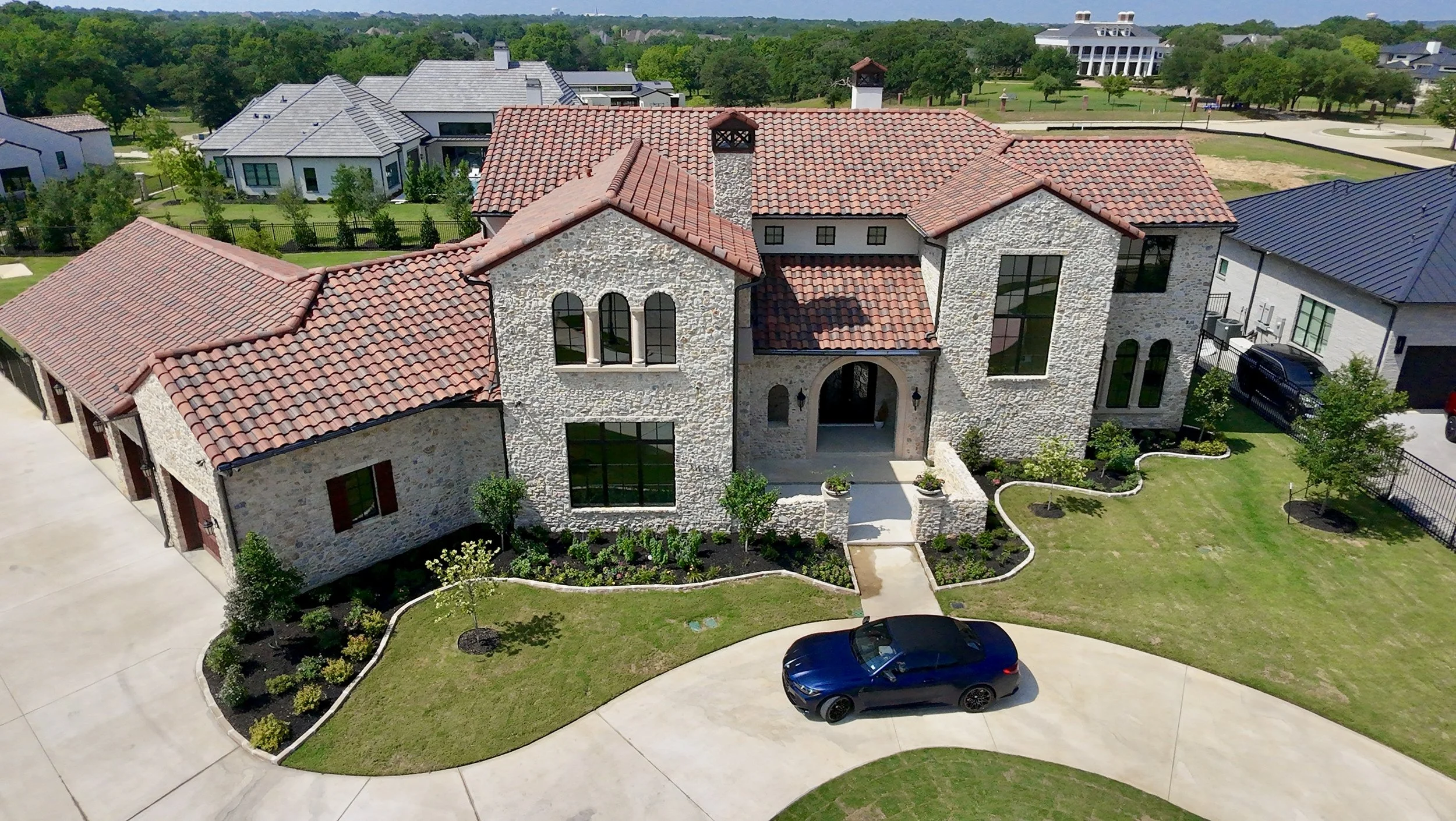 Aerial view of a stone home with red tile roof and landscaped entry in Southlake TX