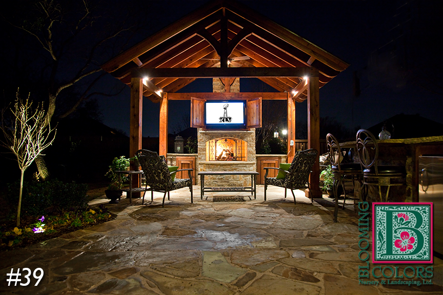 Cedar pavilion with lit fireplace and flagstone patio at night in Grapevine, TX