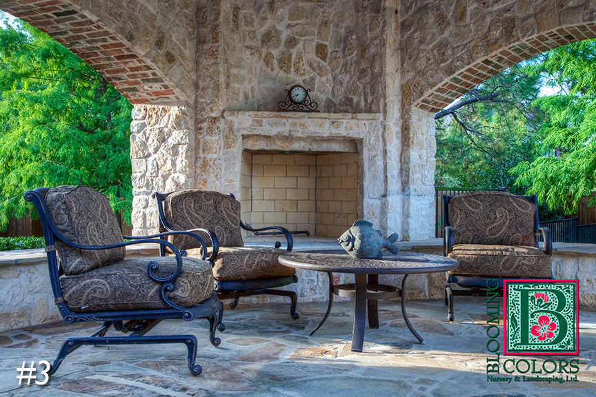 Stone patio with outdoor fireplace and cushioned chairs under an arched stone cover