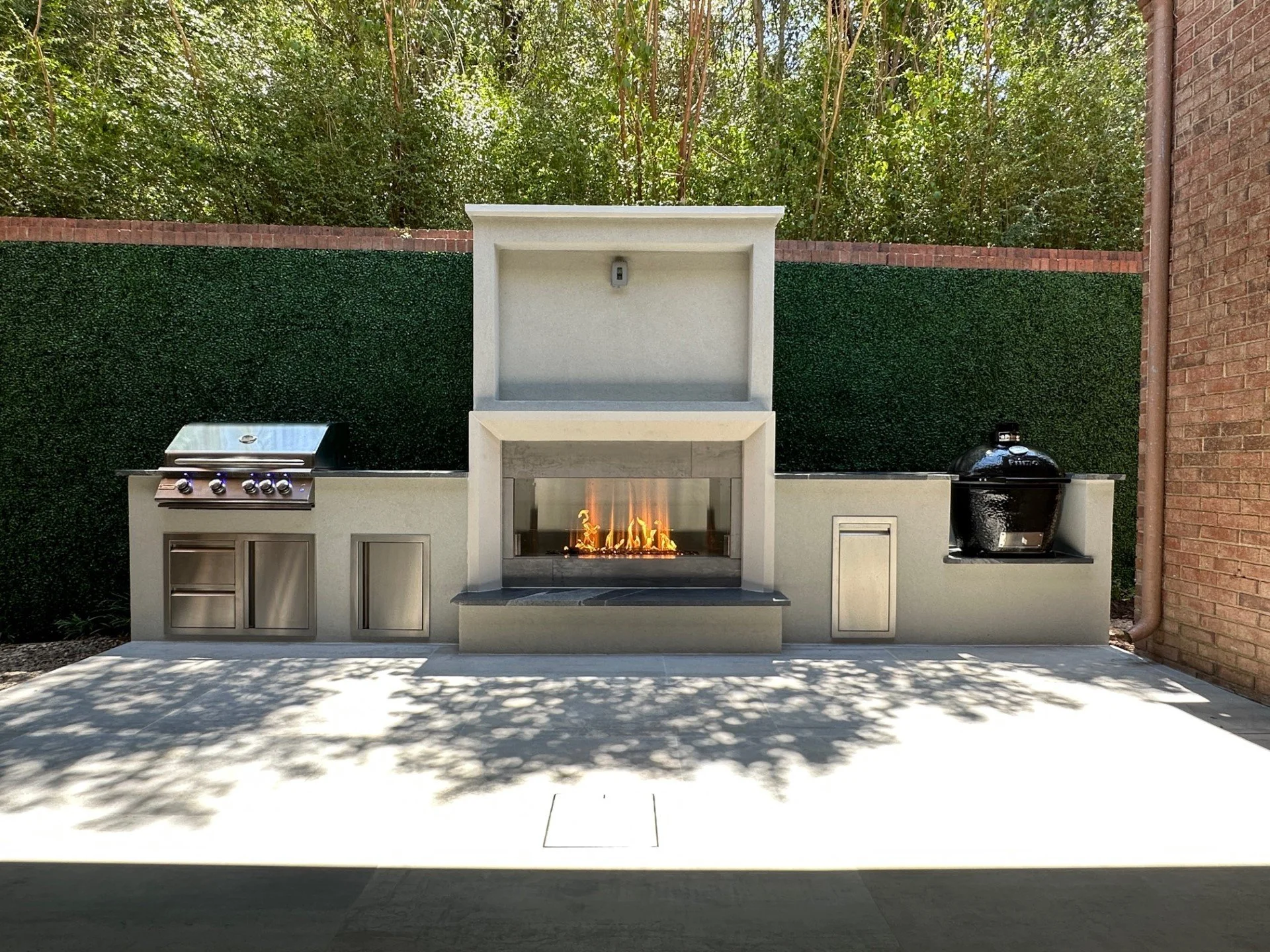 Outdoor fireplace with built-in grill and smoker in a hedge-lined patio in Colleyville, TX