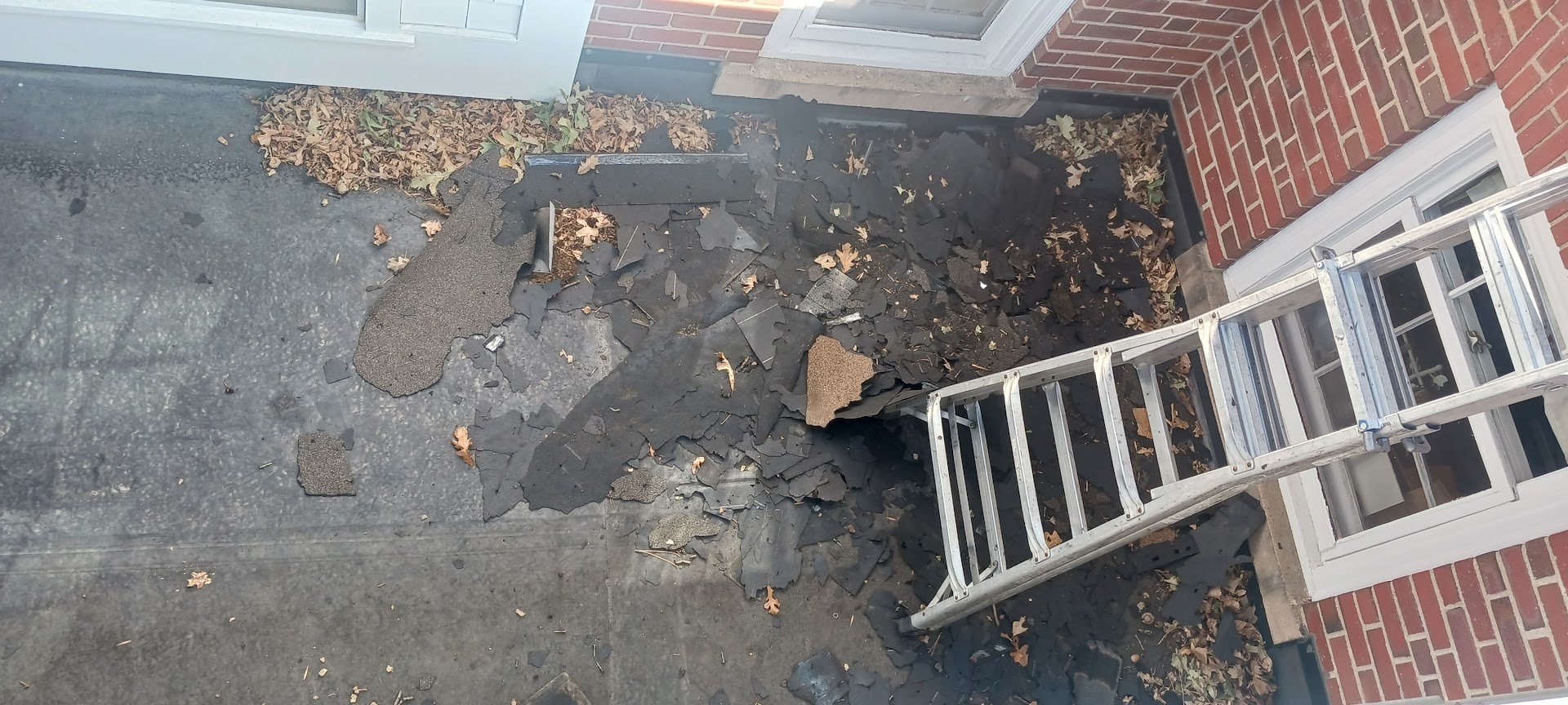 Deteriorated low-slope roof membrane beside a brick exterior wall