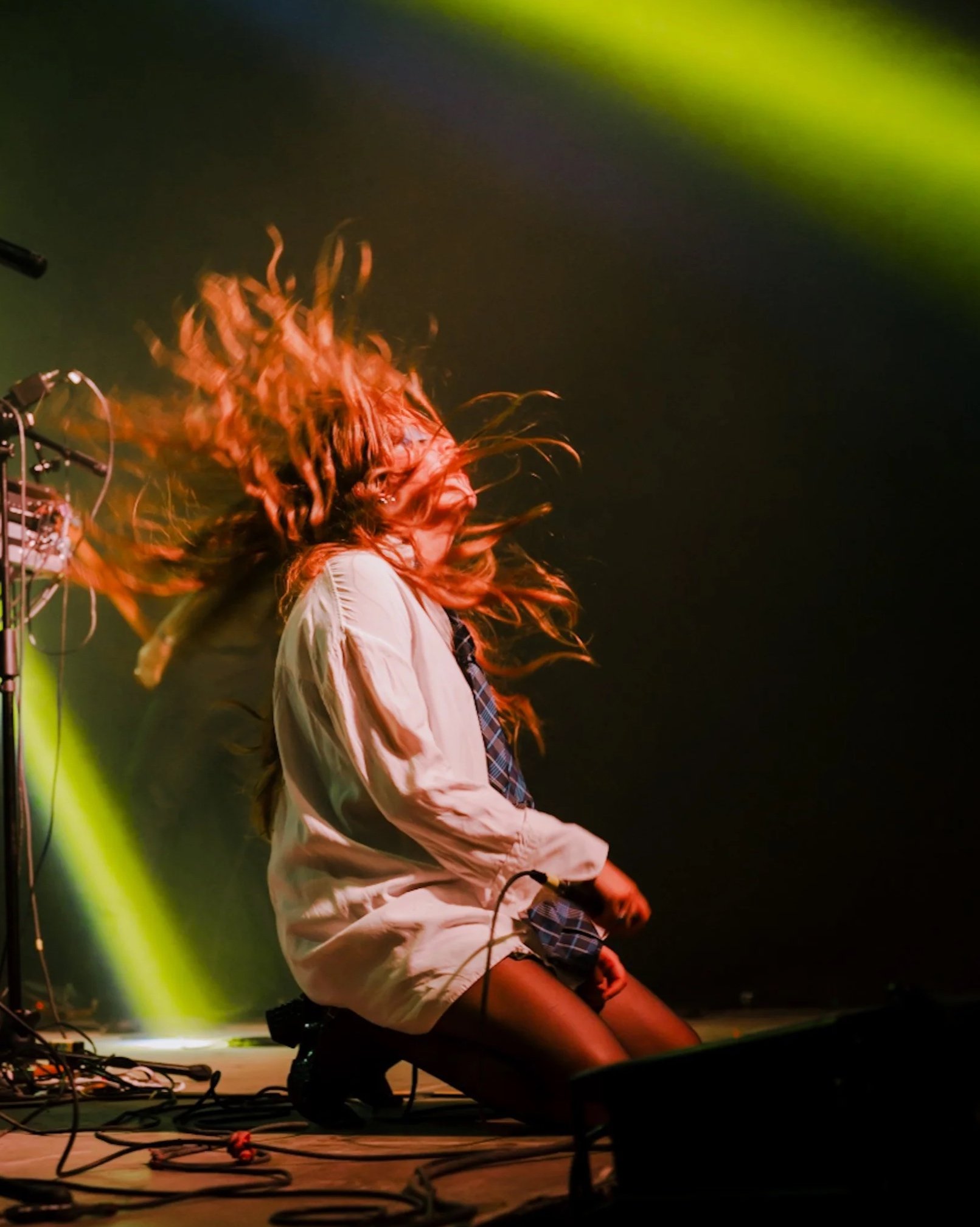 Cantante en movimiento durante un concierto bajo luces verdes.