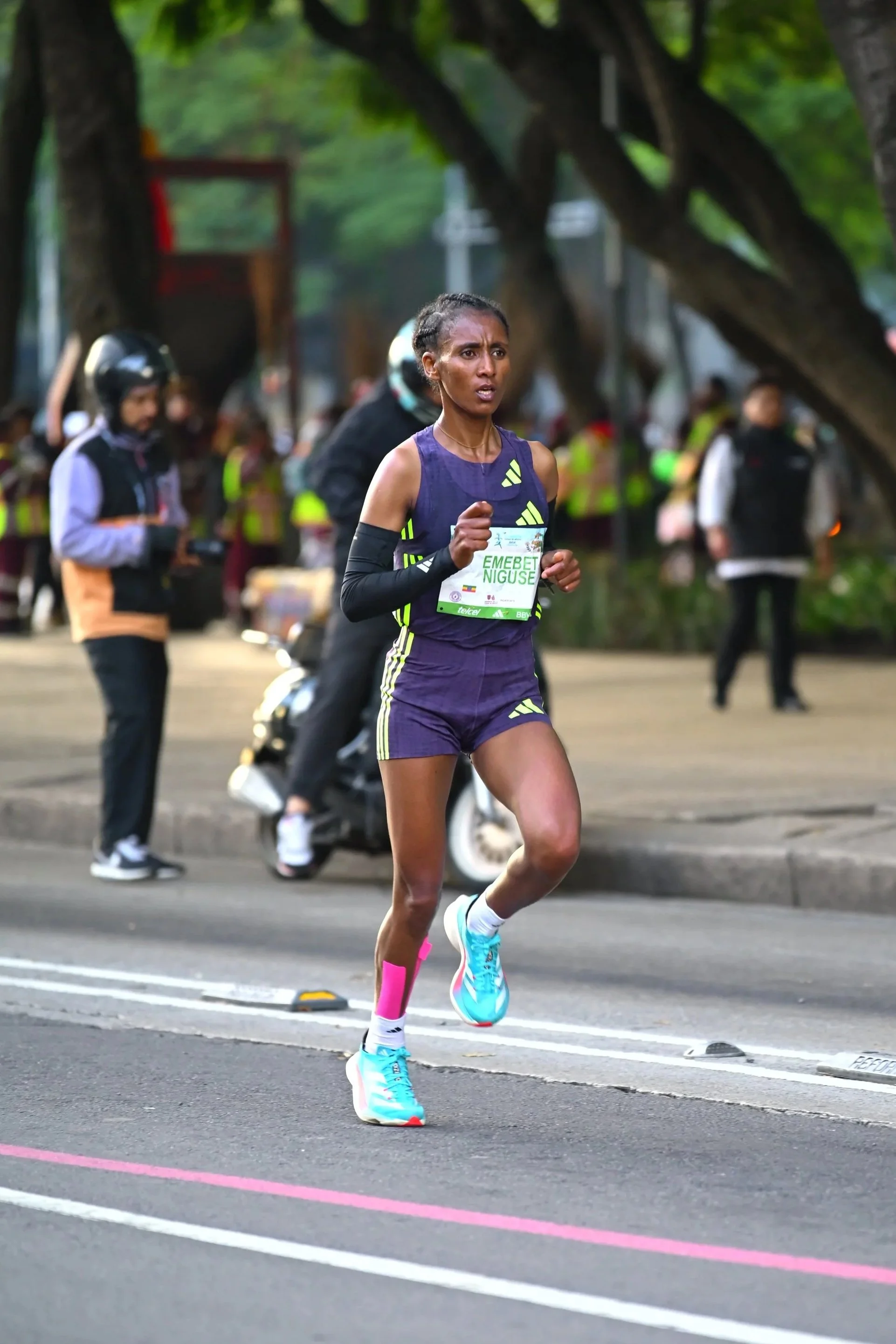 Corredora de uniforme morado avanzando concentrada por la ruta.