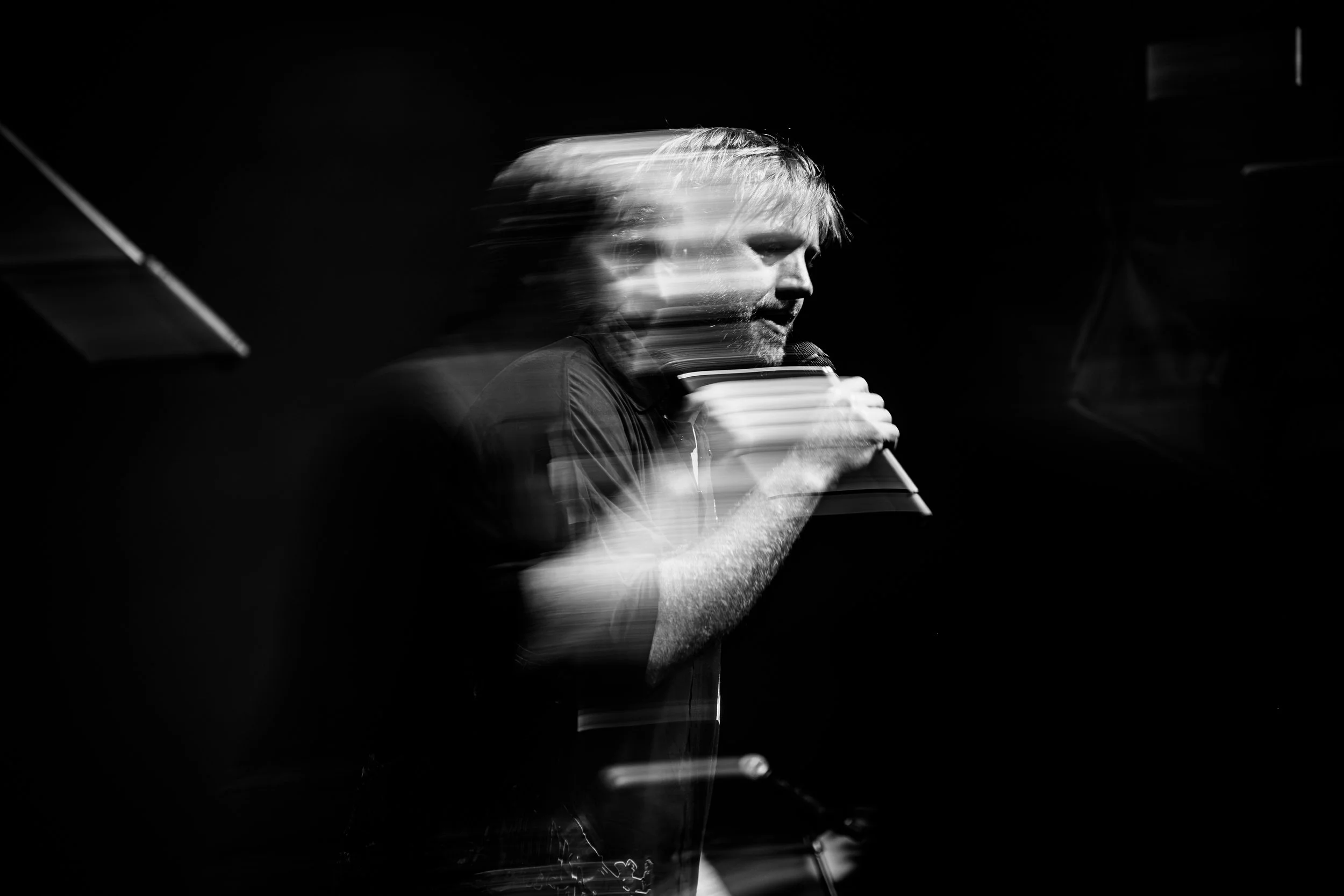 Cantante con micrófono y efecto de movimiento, en blanco y negro.