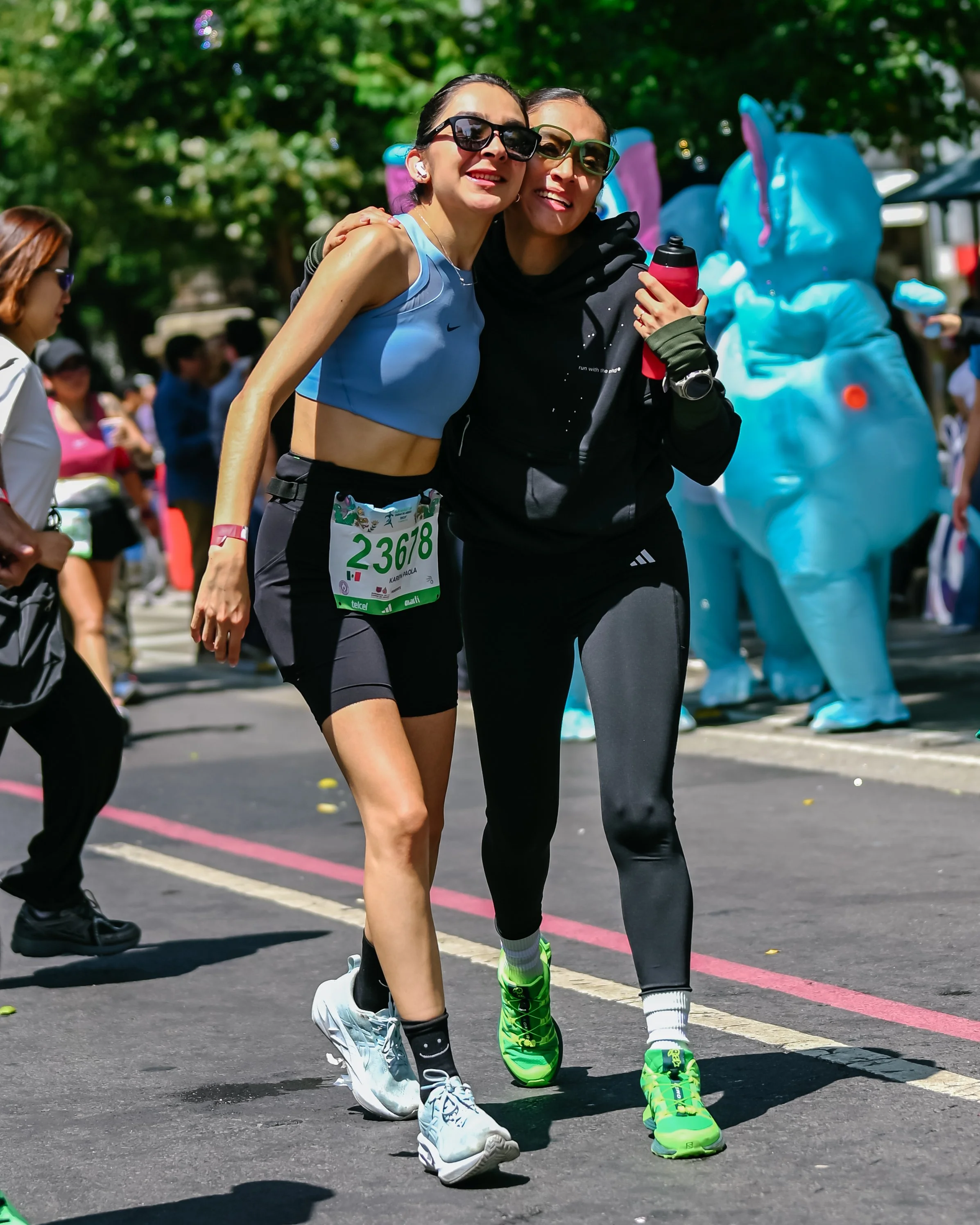 Dos participantes avanzando abrazados durante una carrera.