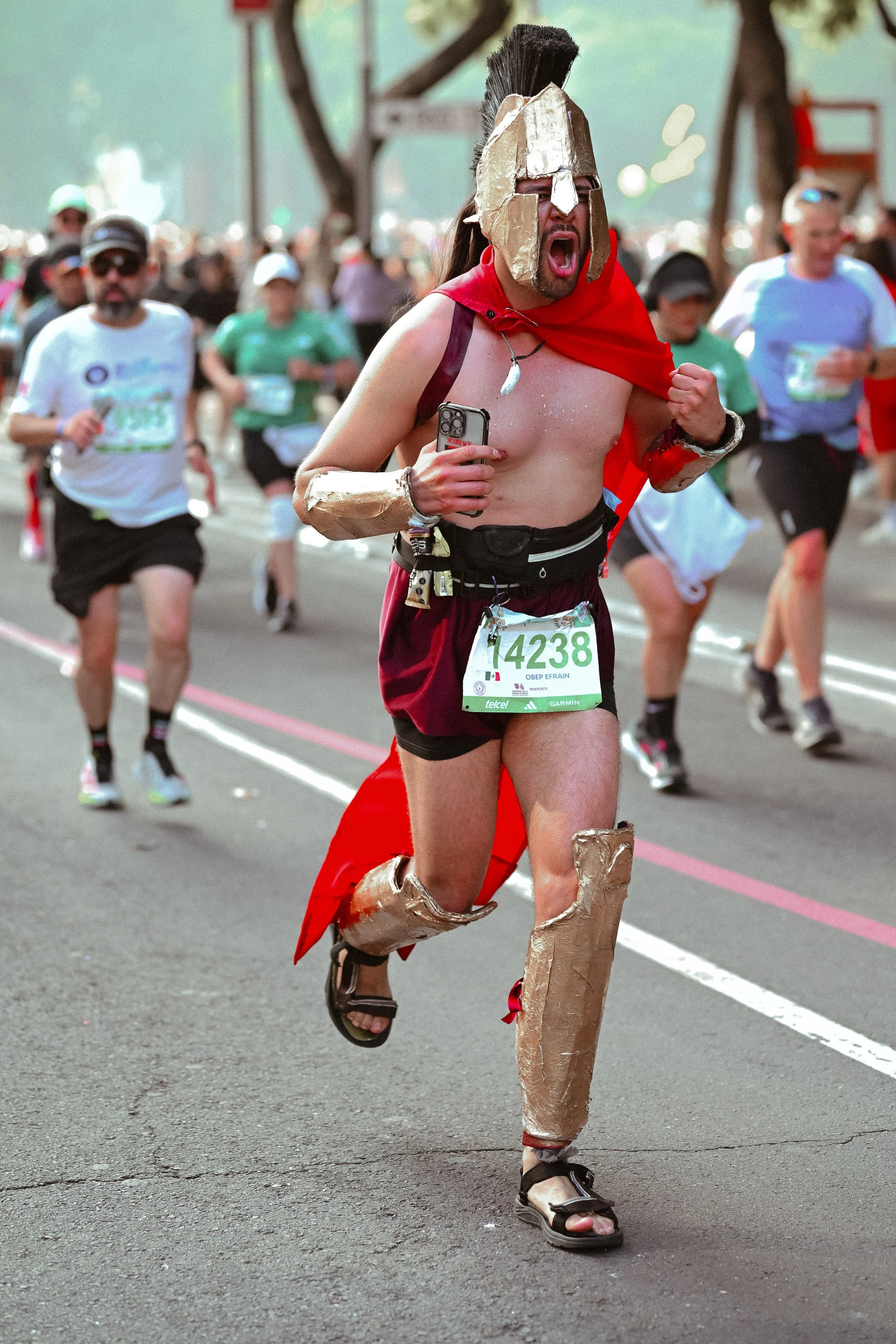 Participante corriendo con disfraz y capa roja entre otros corredores.