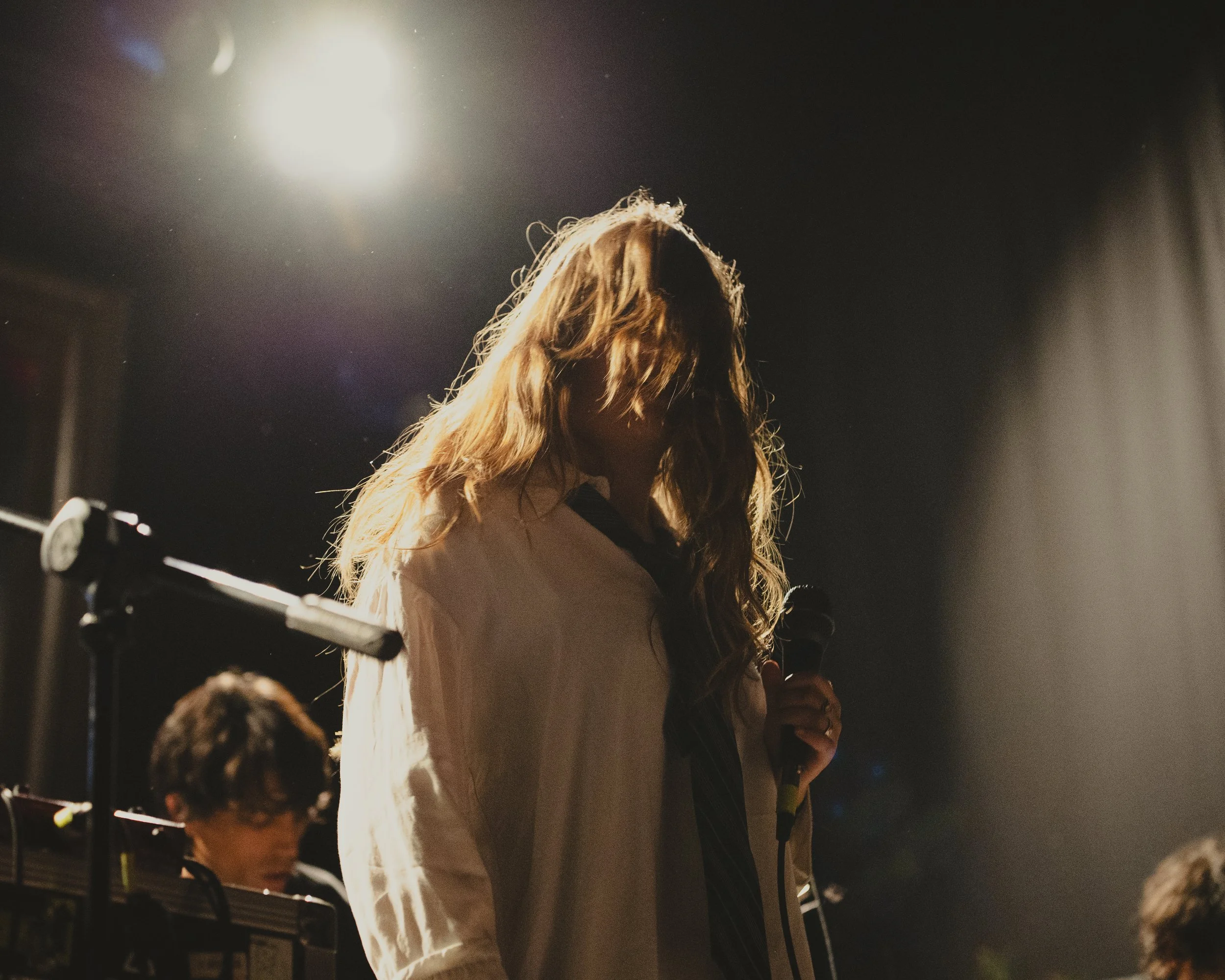 Cantante de cabello largo iluminada desde atrás durante una presentación.