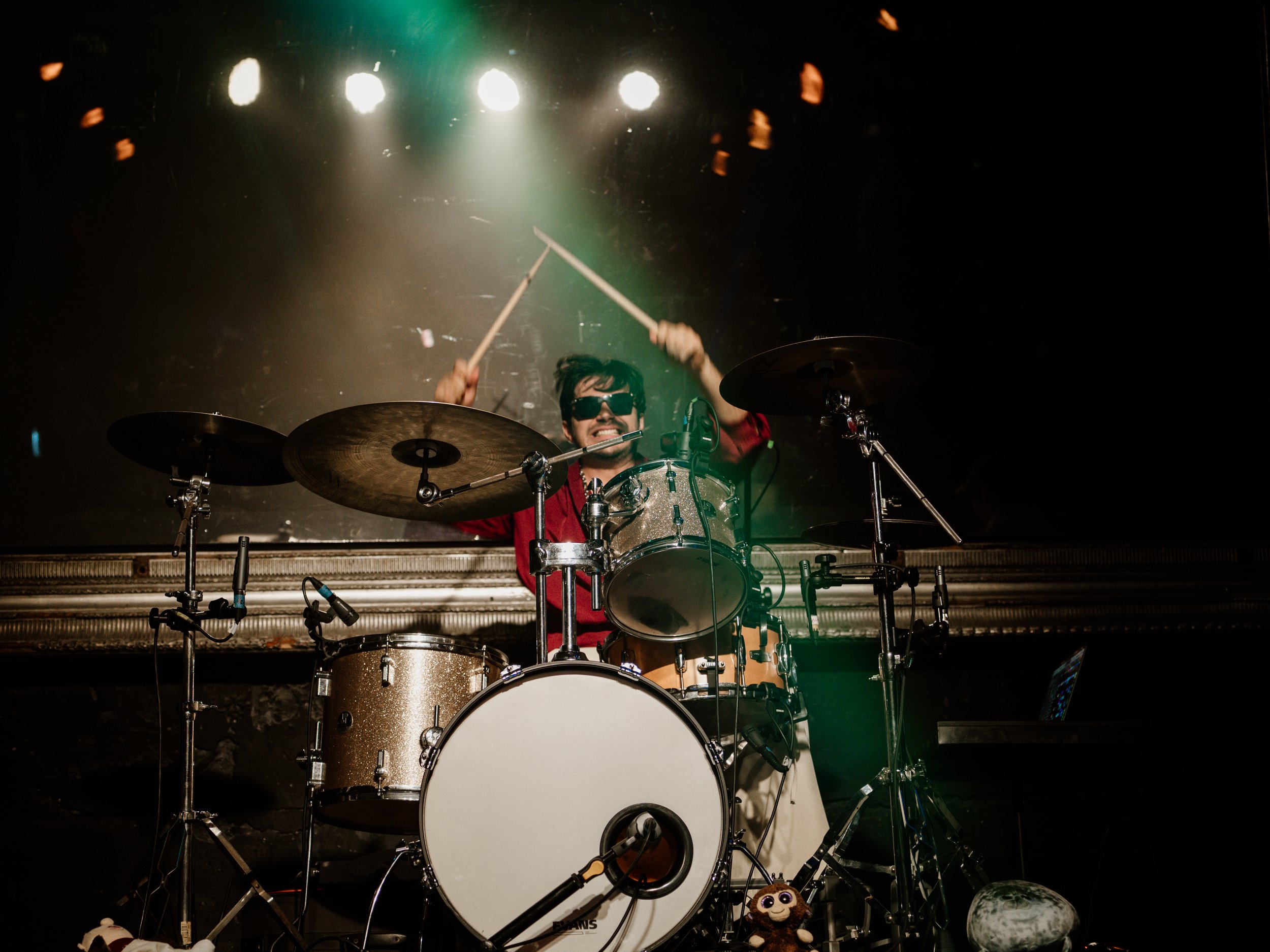 Baterista detrás de su instrumento bajo los reflectores del escenario.