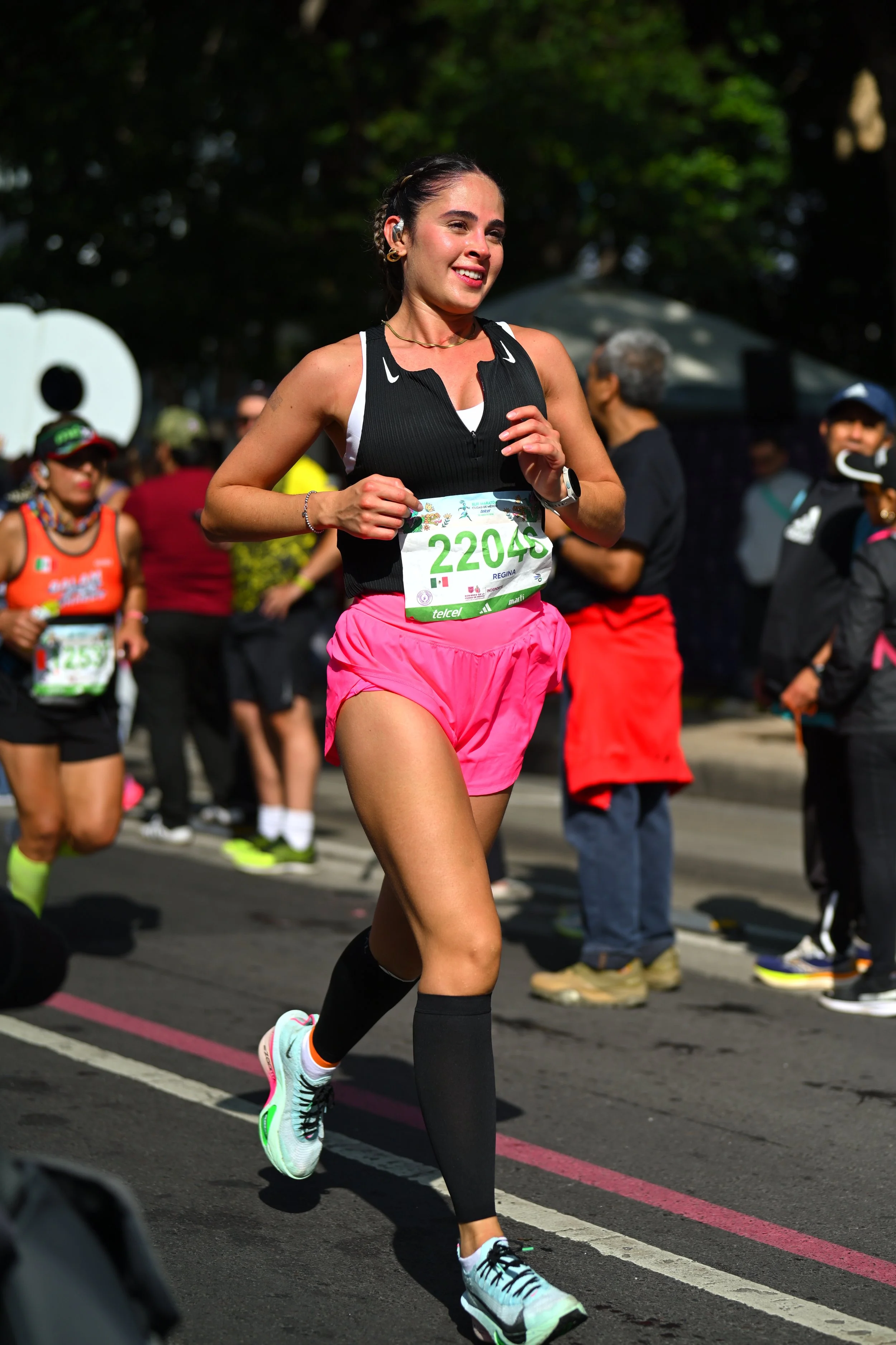 Corredora con shorts rosas y camiseta negra durante una carrera urbana.