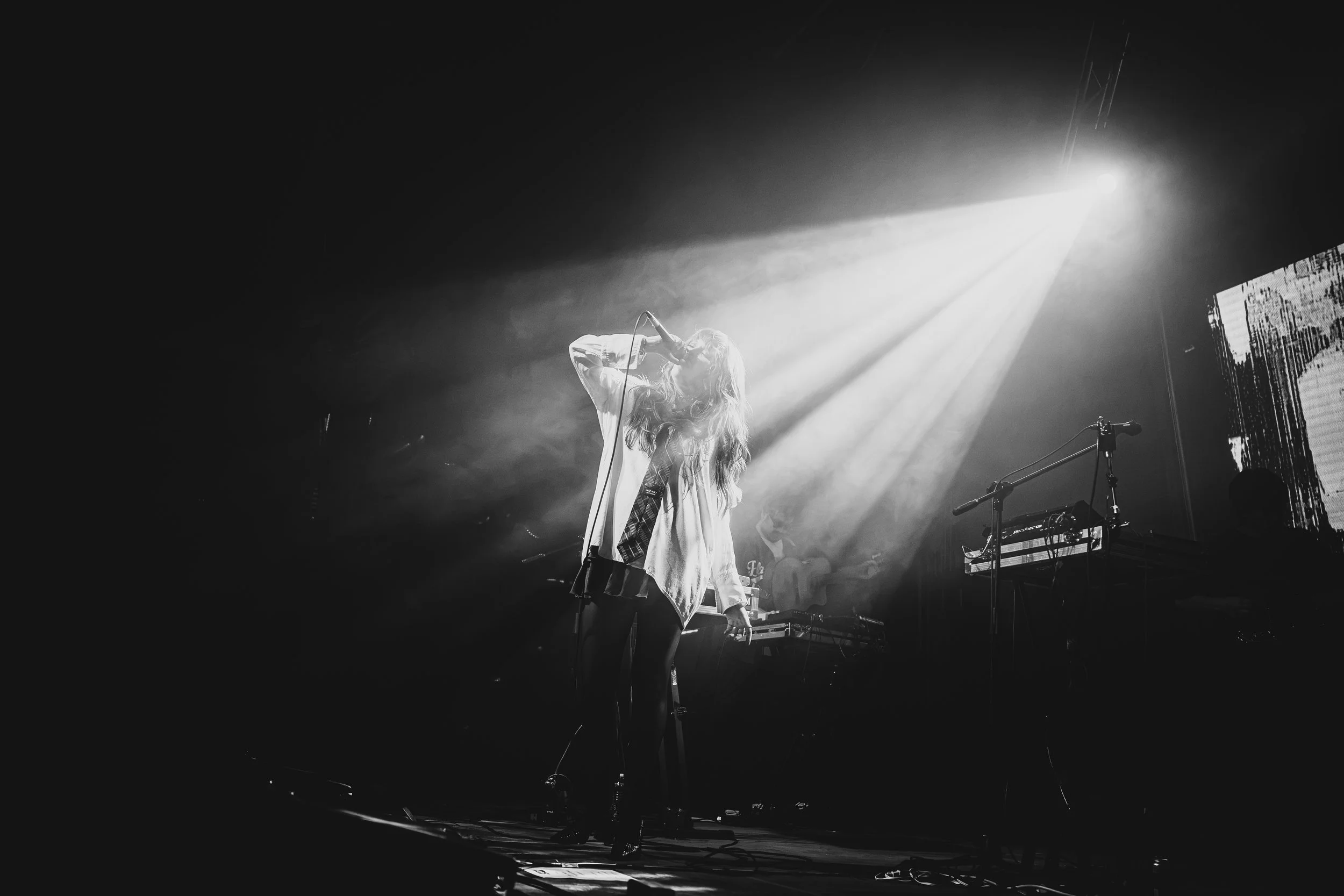 Cantante bajo haces de luz blanca, en blanco y negro.