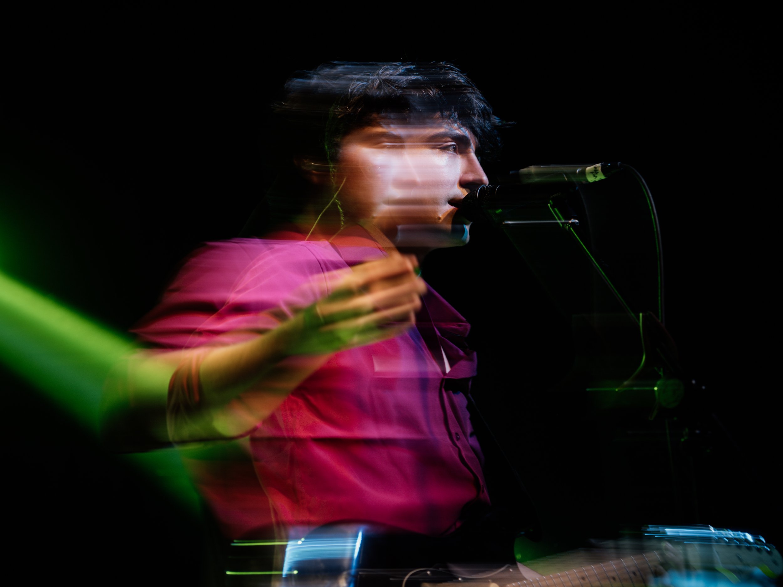 Cantante de camisa roja con efecto de movimiento frente al micrófono.