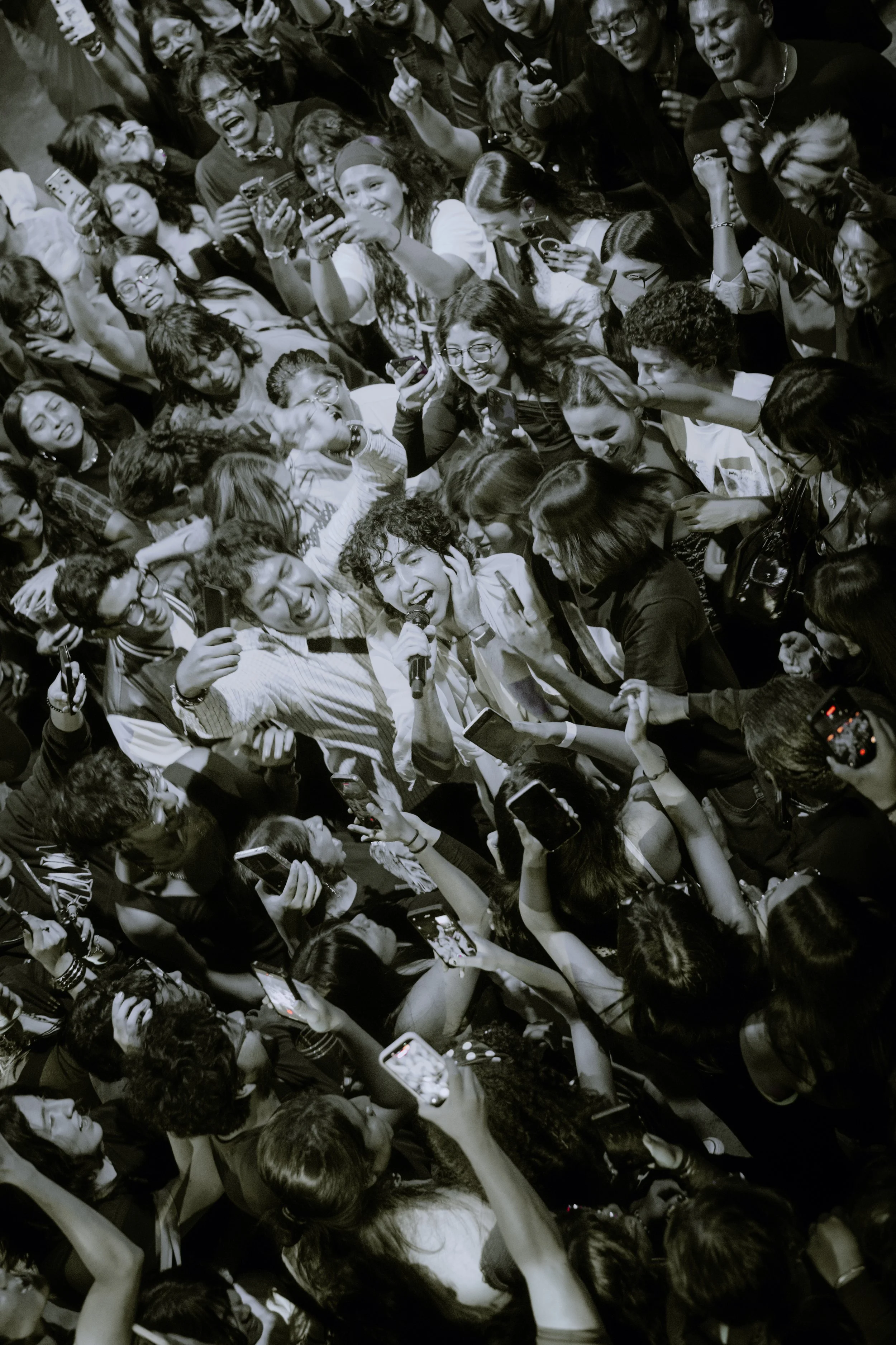 Asistente sostenido en alto por el público del concierto, en blanco y negro.