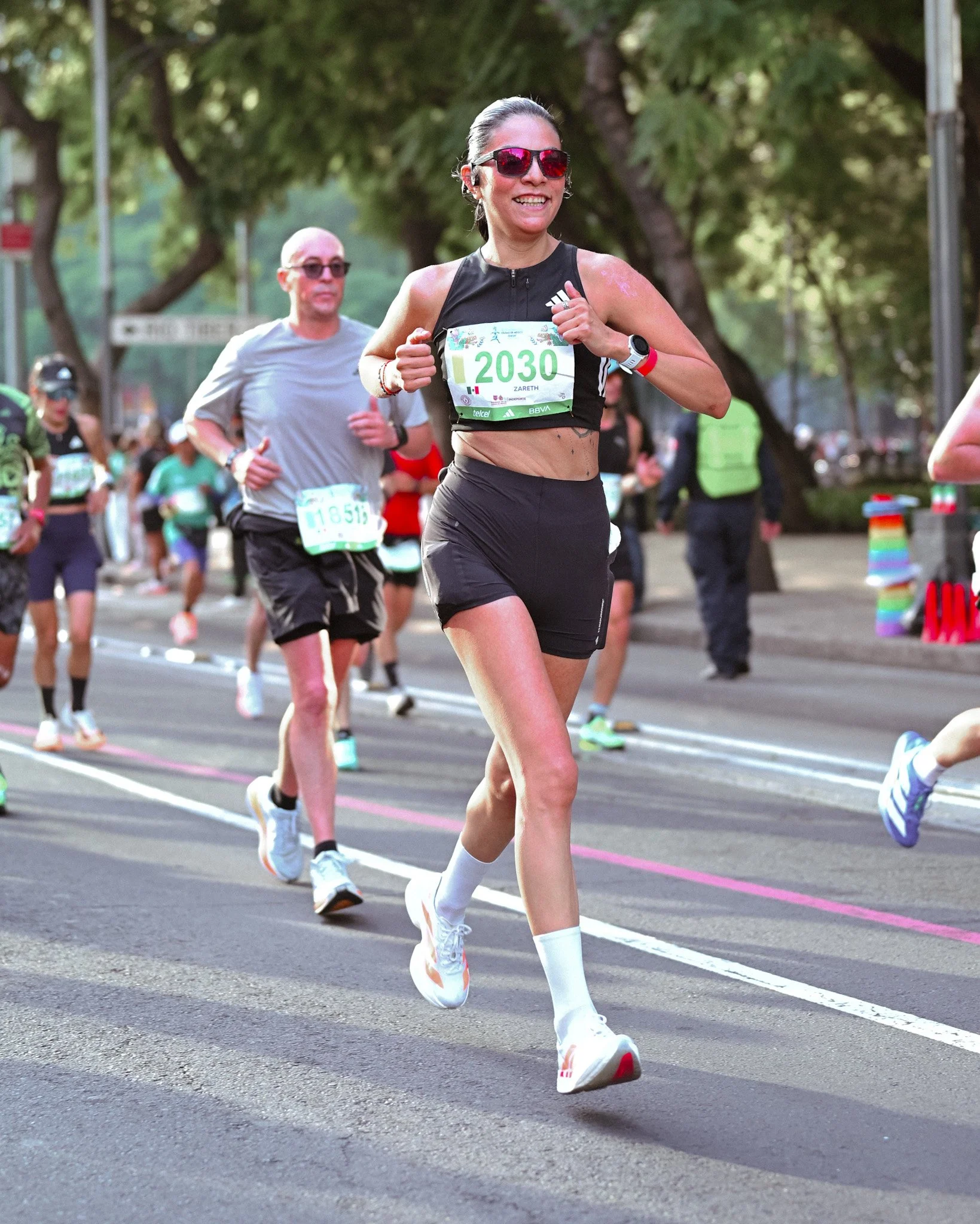 Corredora de conjunto negro y lentes oscuros durante una carrera.