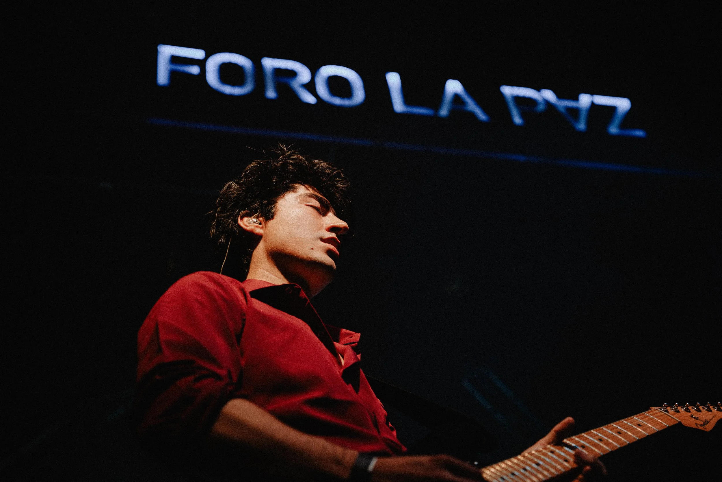 Bajista de camisa roja tocando sobre el escenario de Foro La Paz.