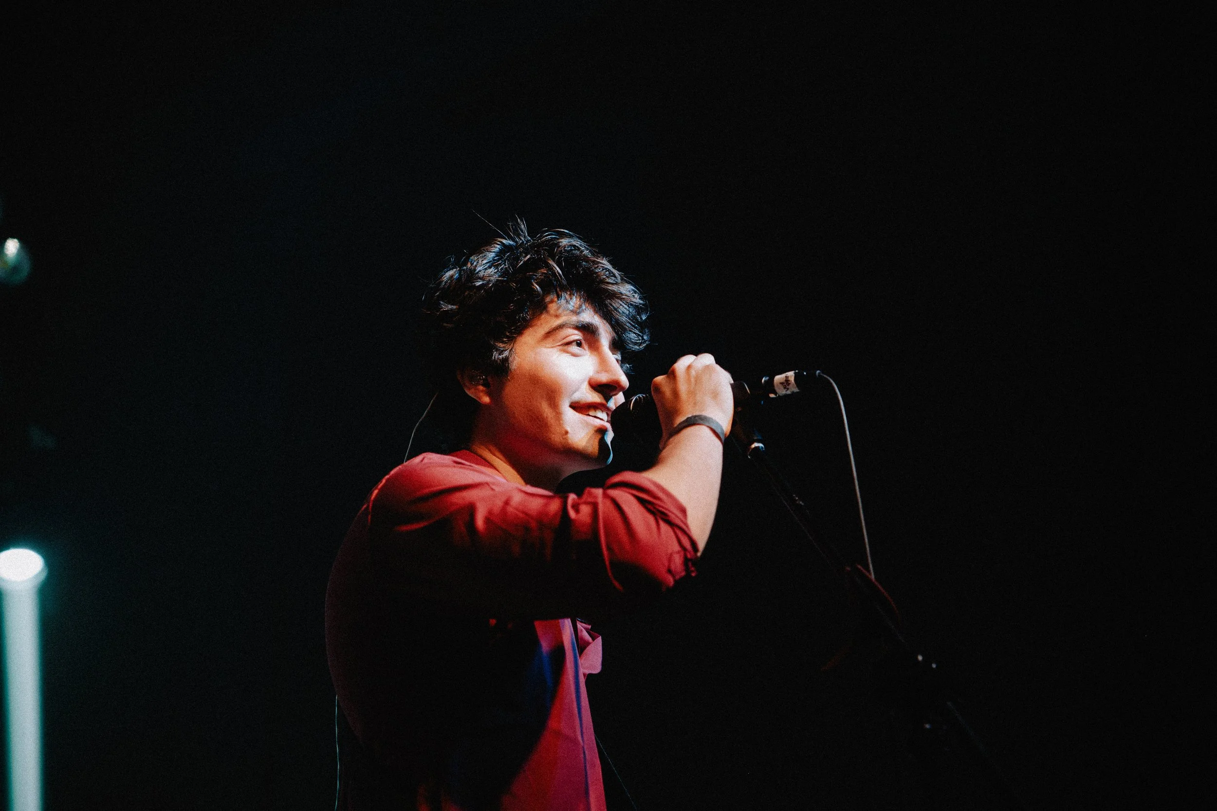 Cantante de camisa roja sosteniendo el micrófono durante su presentación.