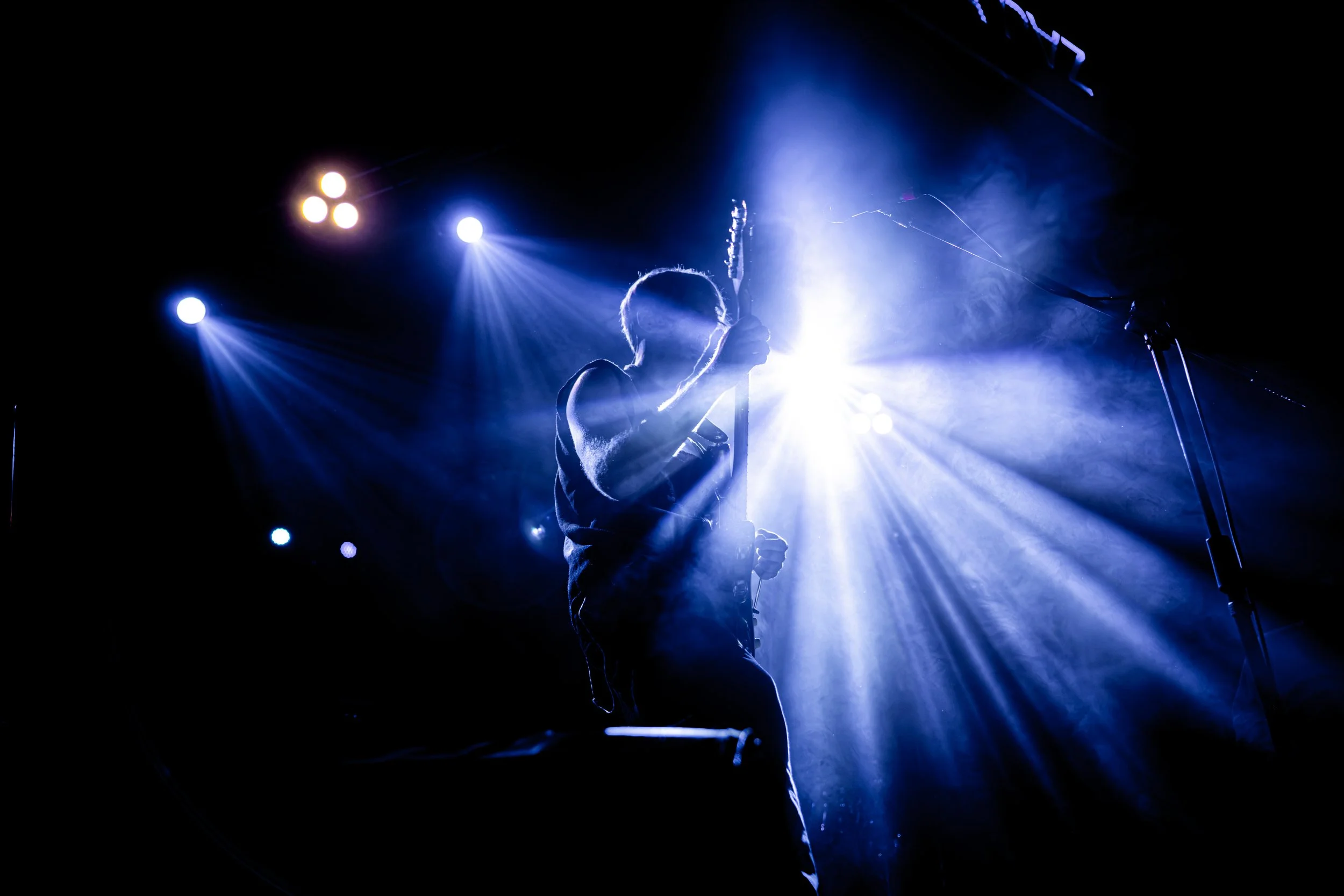 Guitarrista en silueta bajo luces azules durante un concierto.