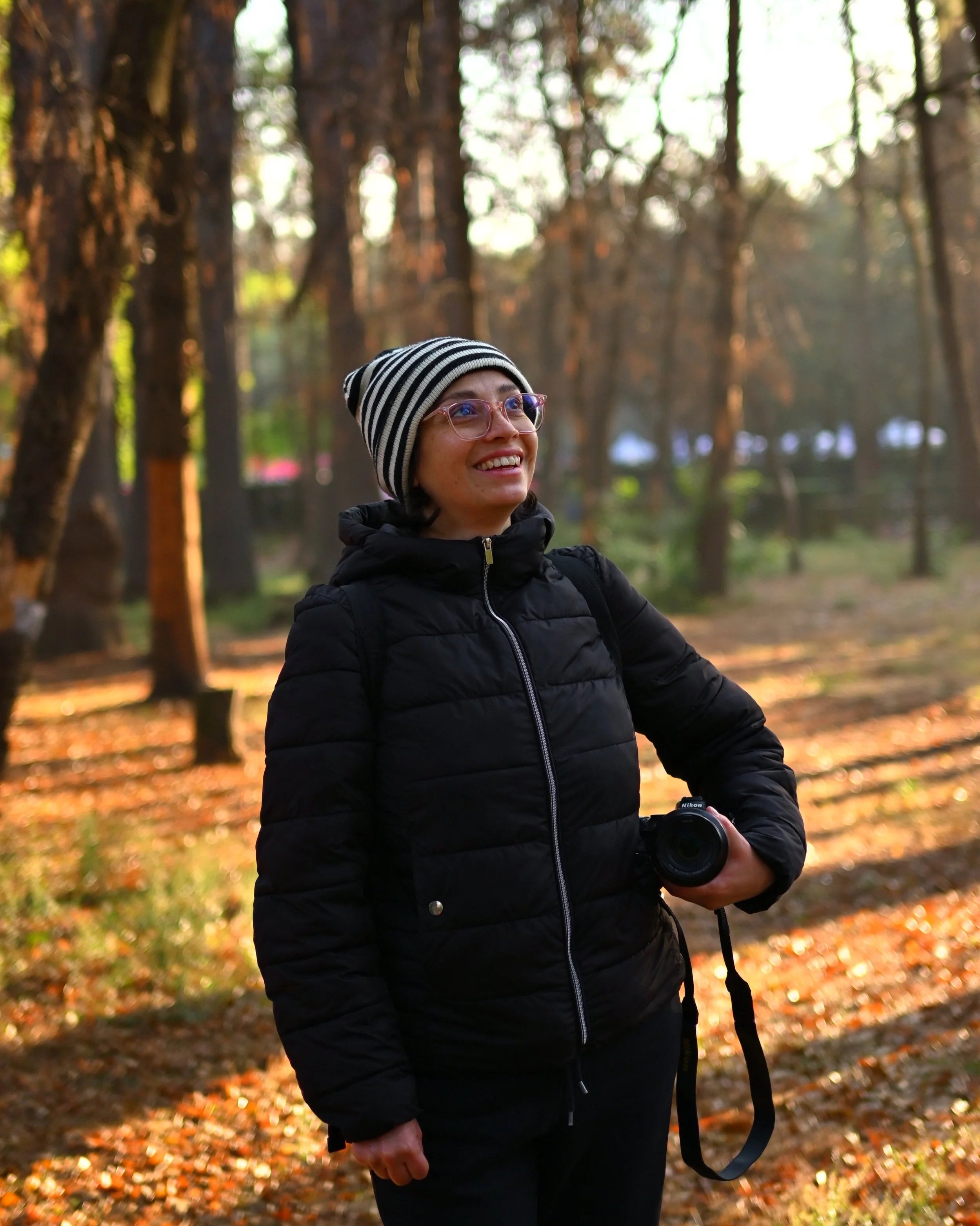Sandybelle Garcilazo sonriendo en un bosque mientras sostiene su cámara.