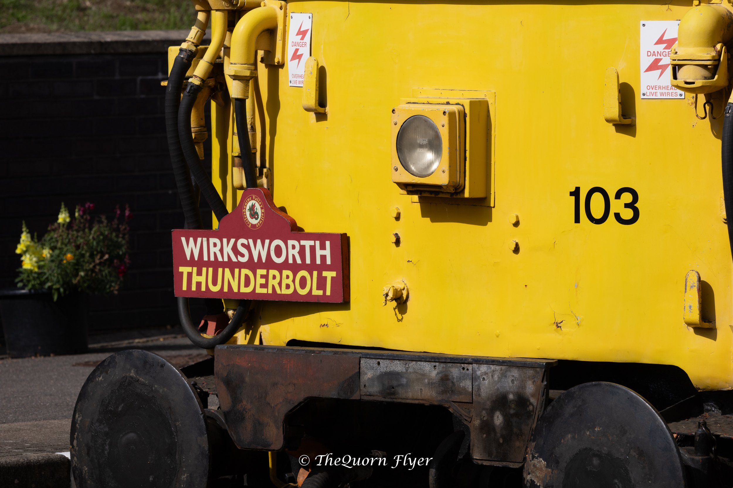 A yellow electrical box with warning signs and black cables, featuring a red sign for Wirksworth Thunderbolt.