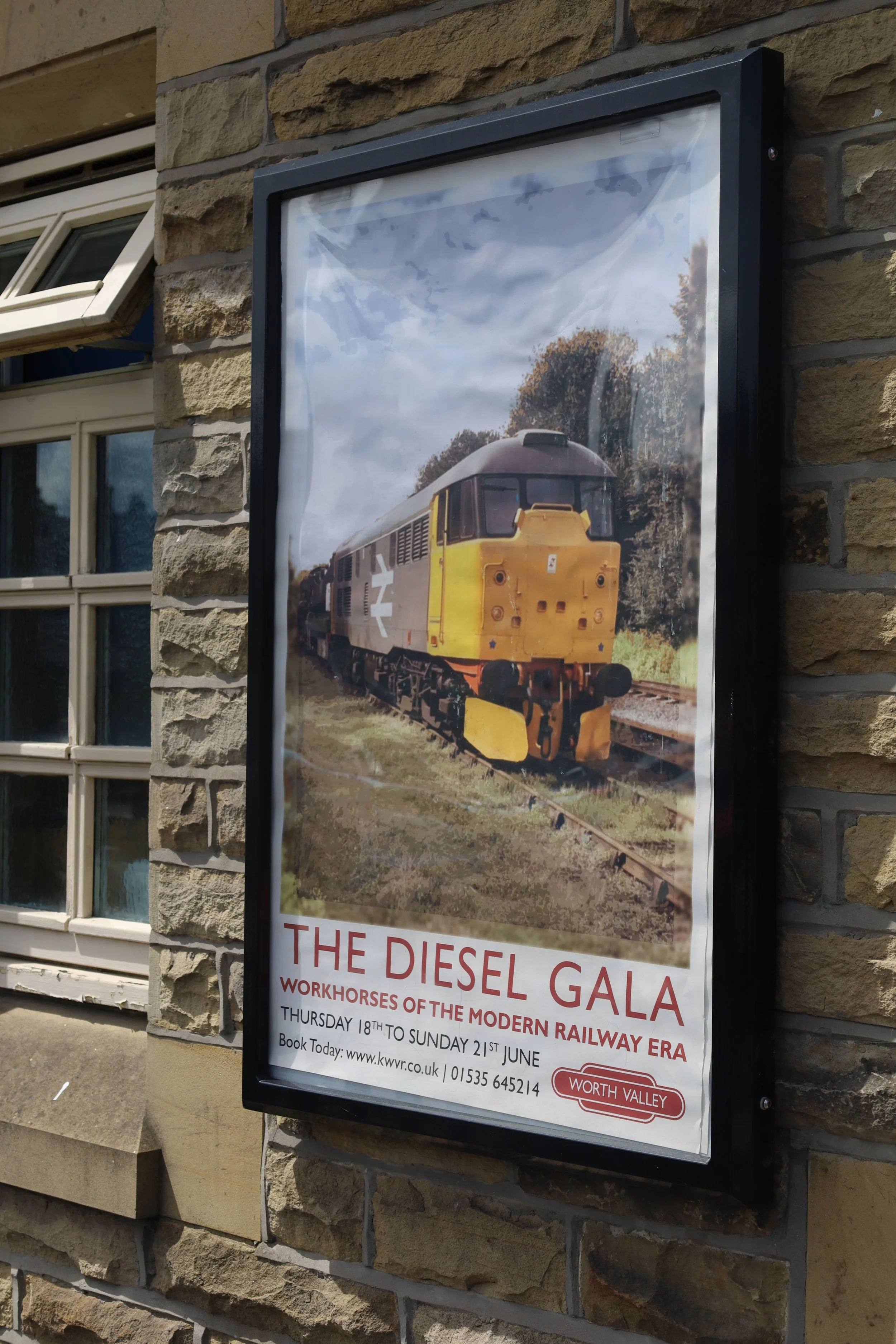 A poster on a brick wall advertising the Diesel Gala, featuring a photo of a diesel train on railway tracks with trees in the background. The event is scheduled from Thursday, June 18th to Sunday, June 21st.
