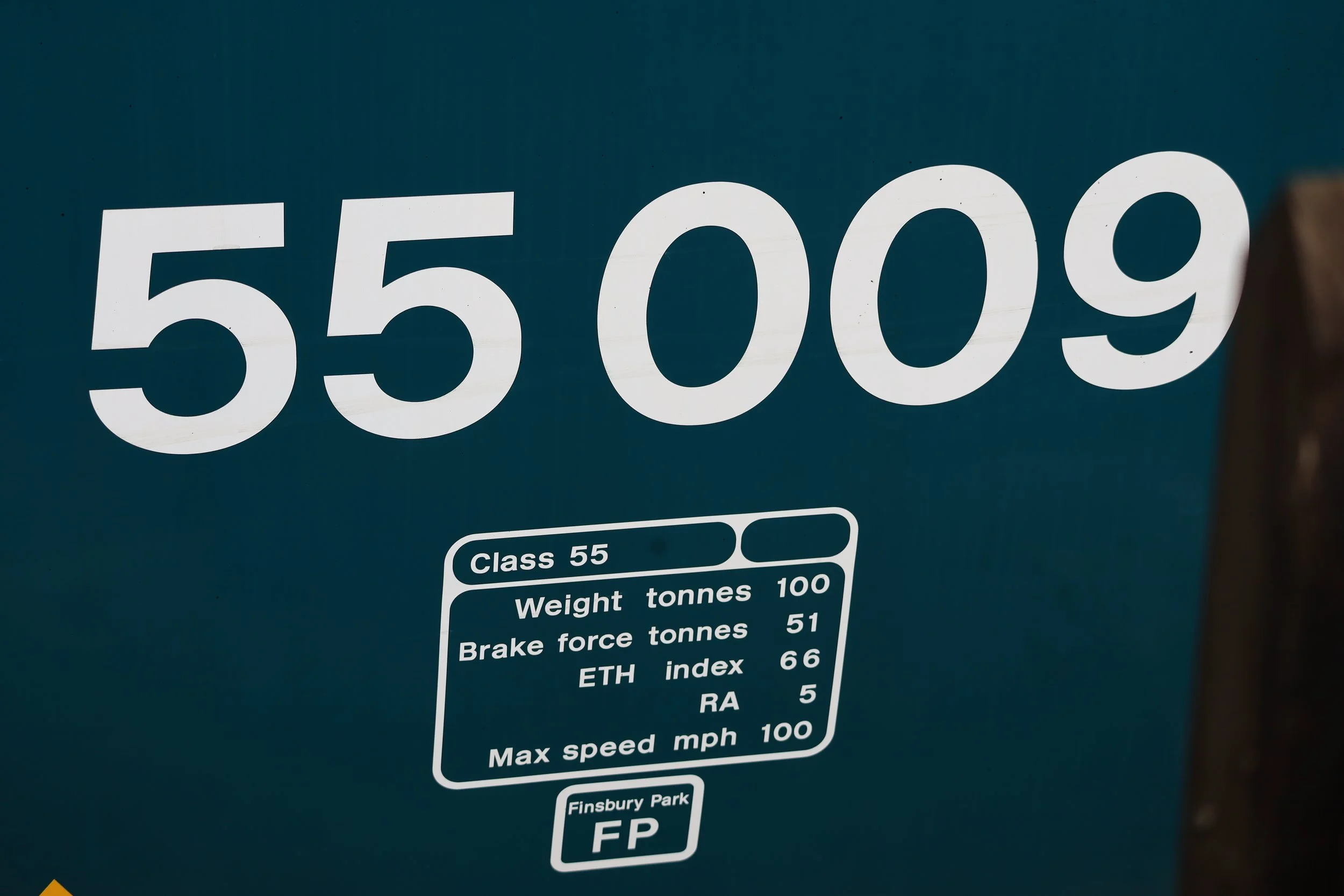 Close-up of a blue sign with large white numbers '55 009' and additional information about weight, brake force, and other specifications.