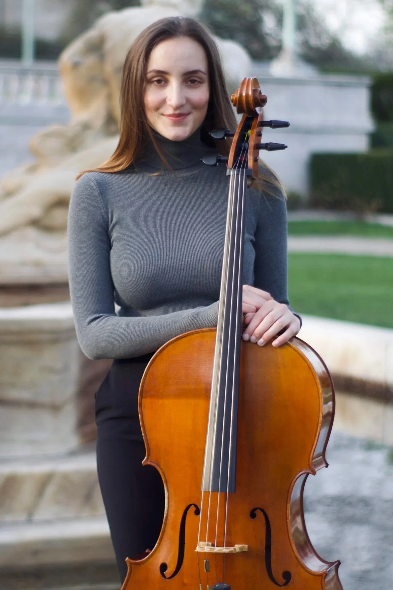 Woman standing outdoors with a cello