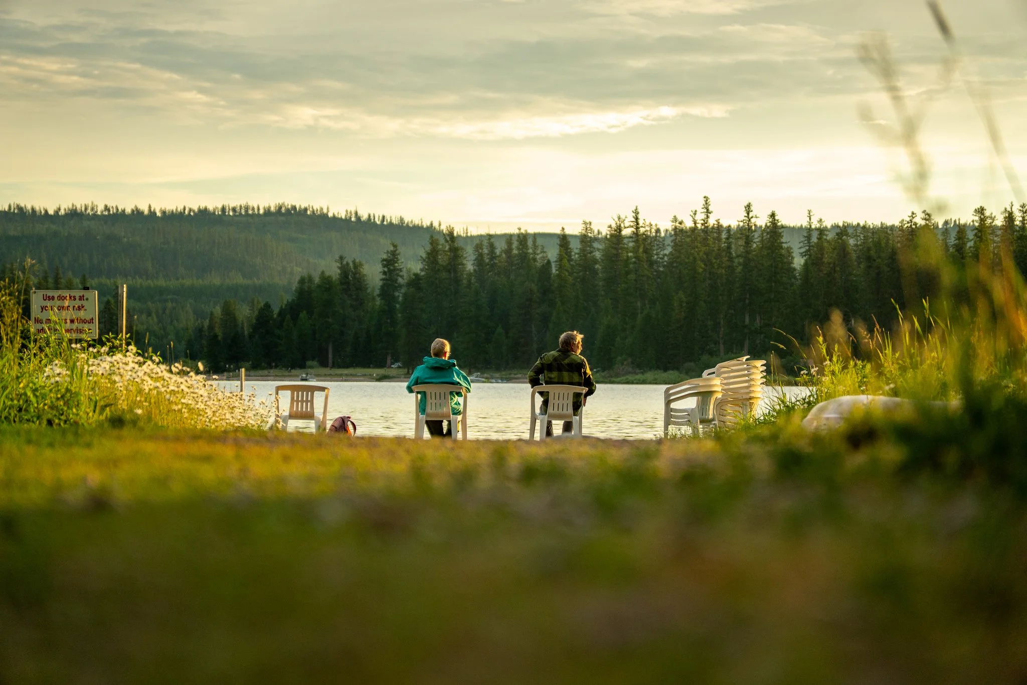 Two men sitting by a lake at sunset