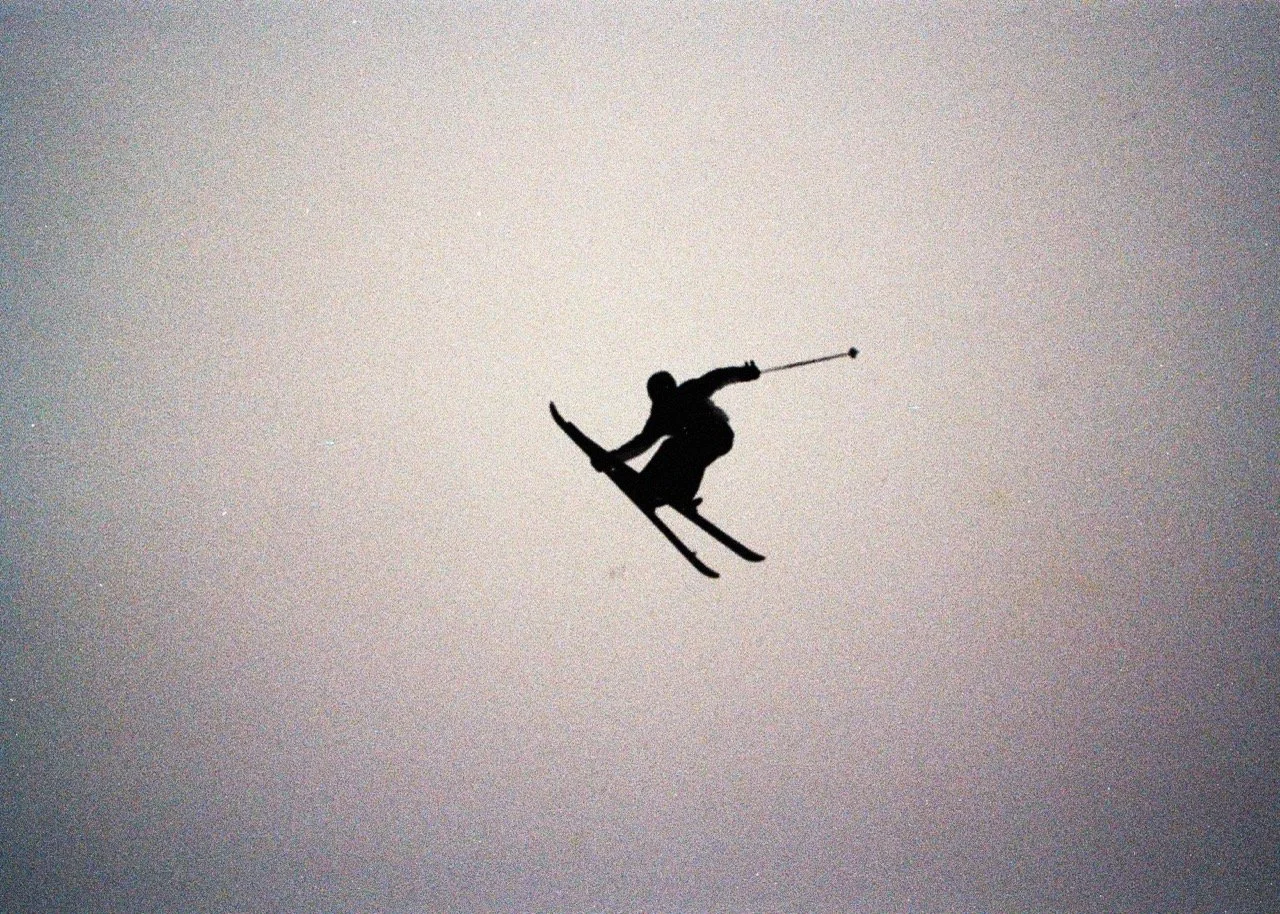 35mm Film photo of Skier silhouette on ski doing a grab  
