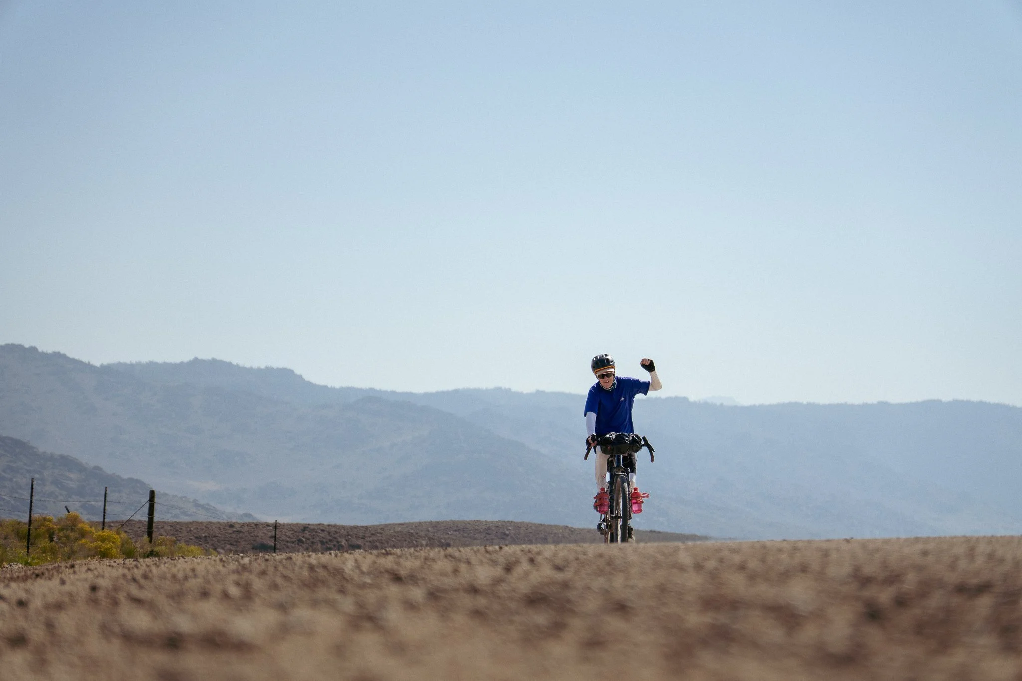 Bike packer raising fist coming over a hill