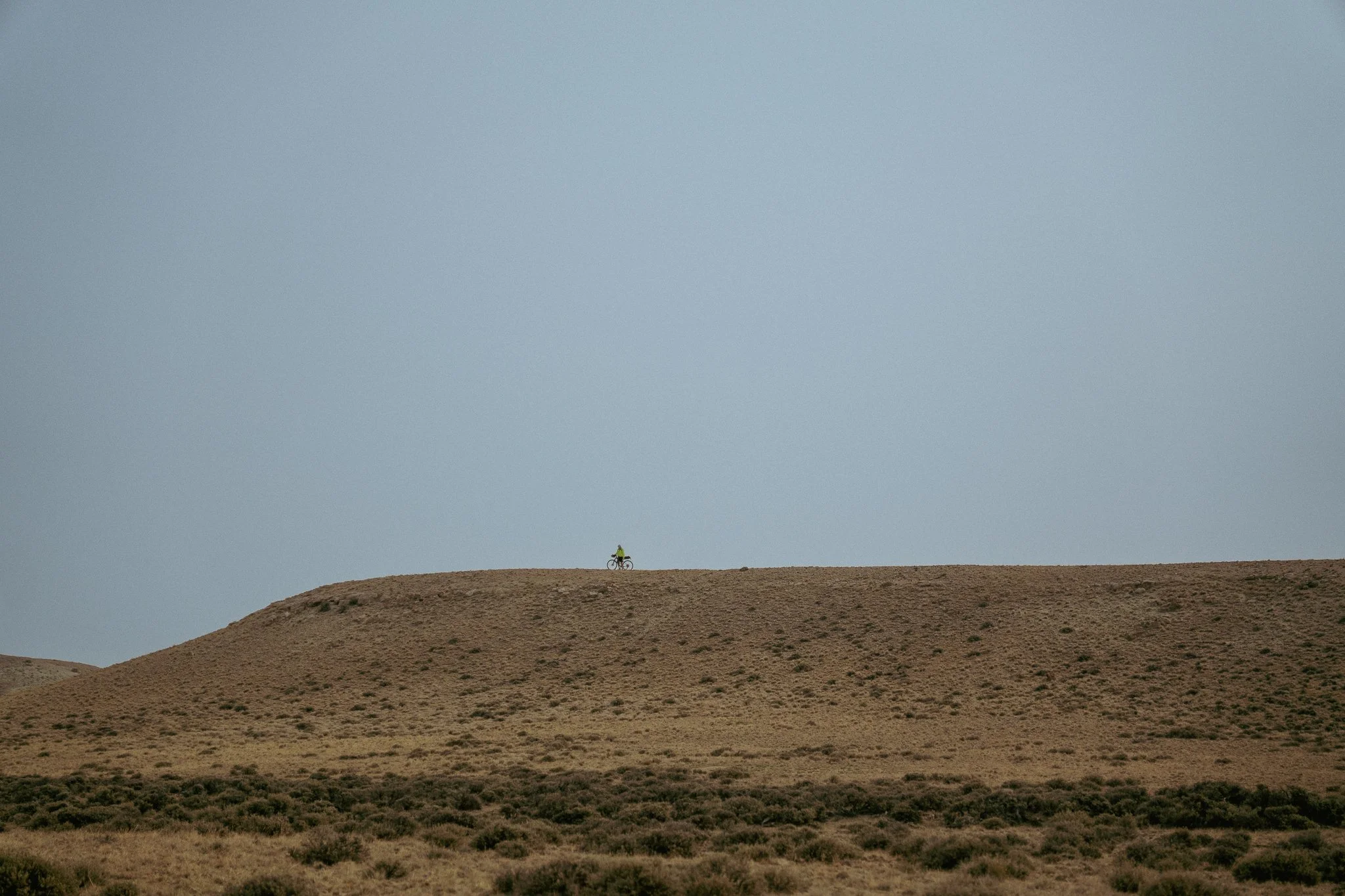 A bike packer far away on a mesa in the Wyoming desert