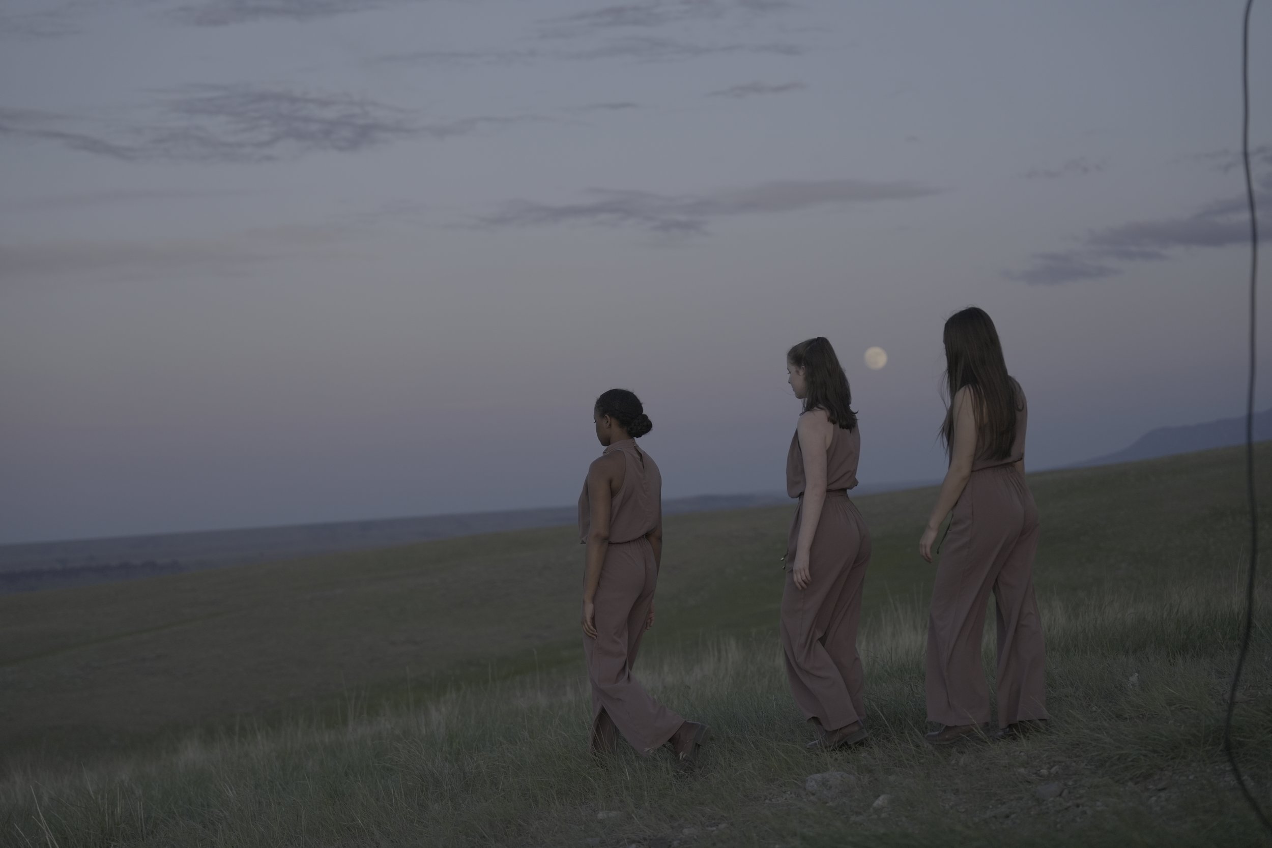 Dancers walking in front of the moon