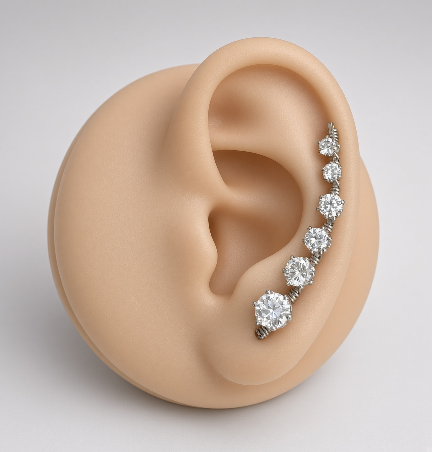 Close-up of a mannequin ear wearing a silver ear climber earring with five sparkling round gemstones