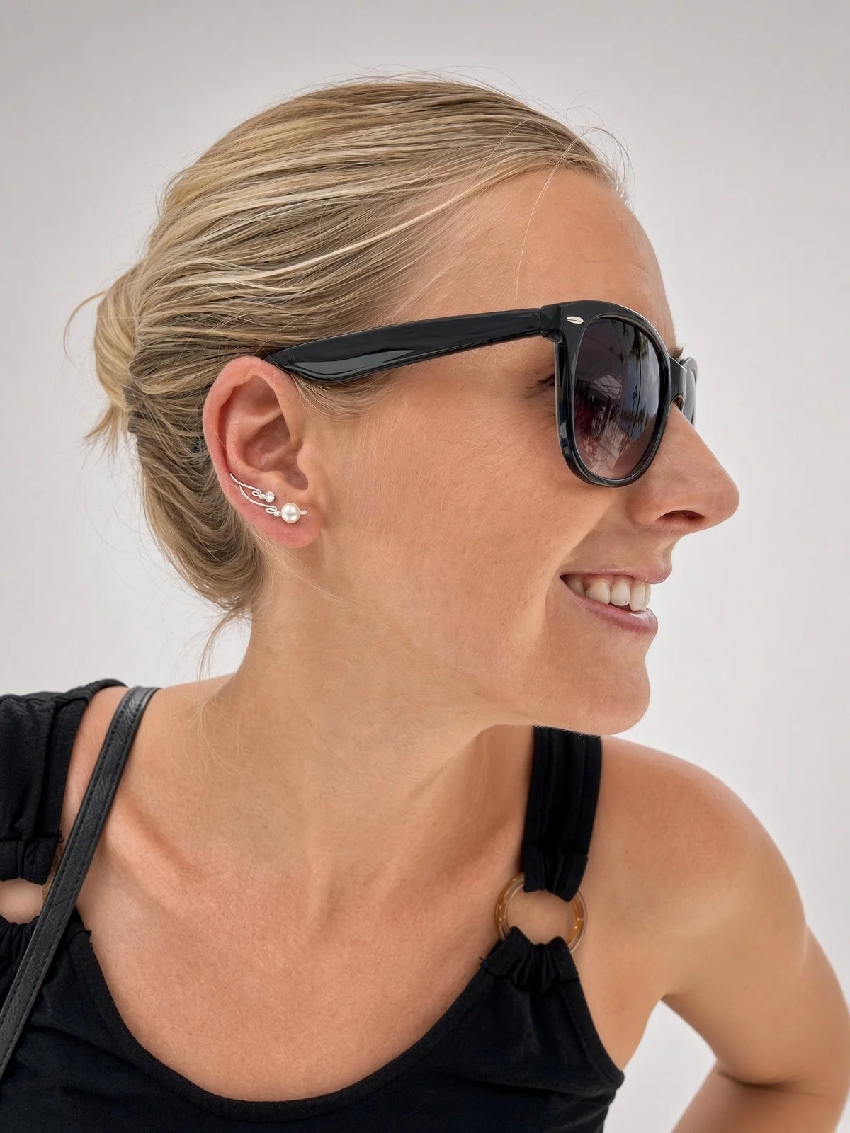 Smiling woman wearing black sunglasses and pearl ear cuff jewelry