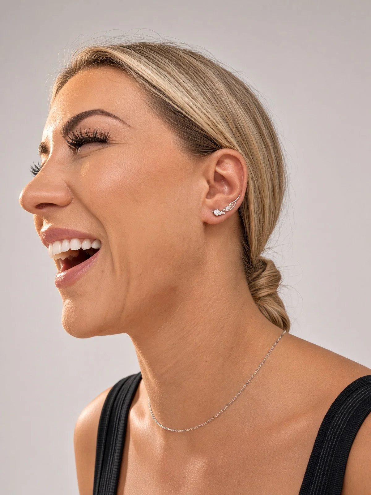Smiling woman in profile wearing a delicate silver ear climber earring and necklace