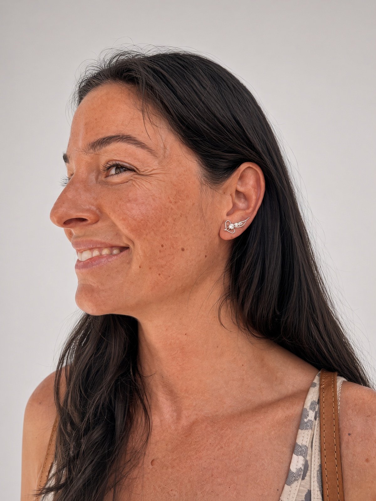 Smiling woman with long dark hair wearing a silver rabbit-shaped stud earring
