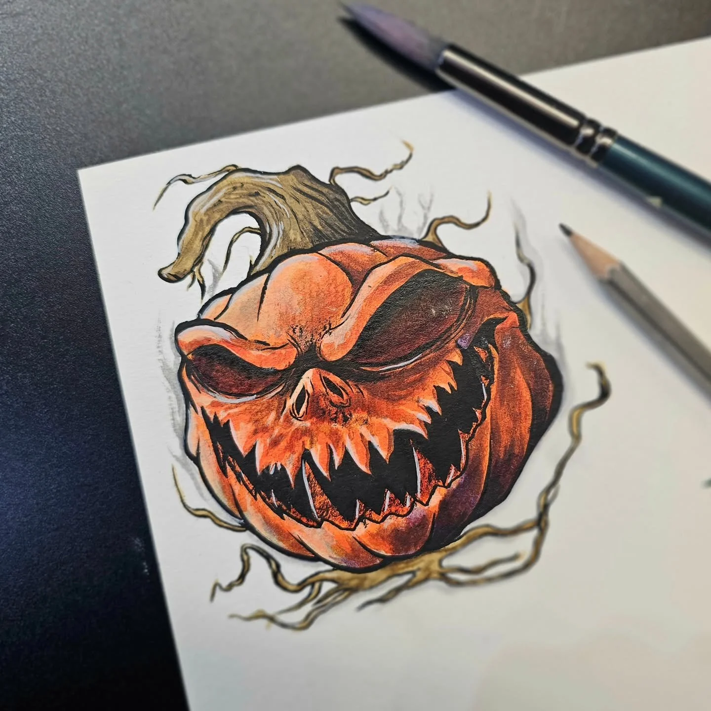 Colorful drawing of a pumpkin with a menacing skull face, surrounded by twisted branches, on paper.