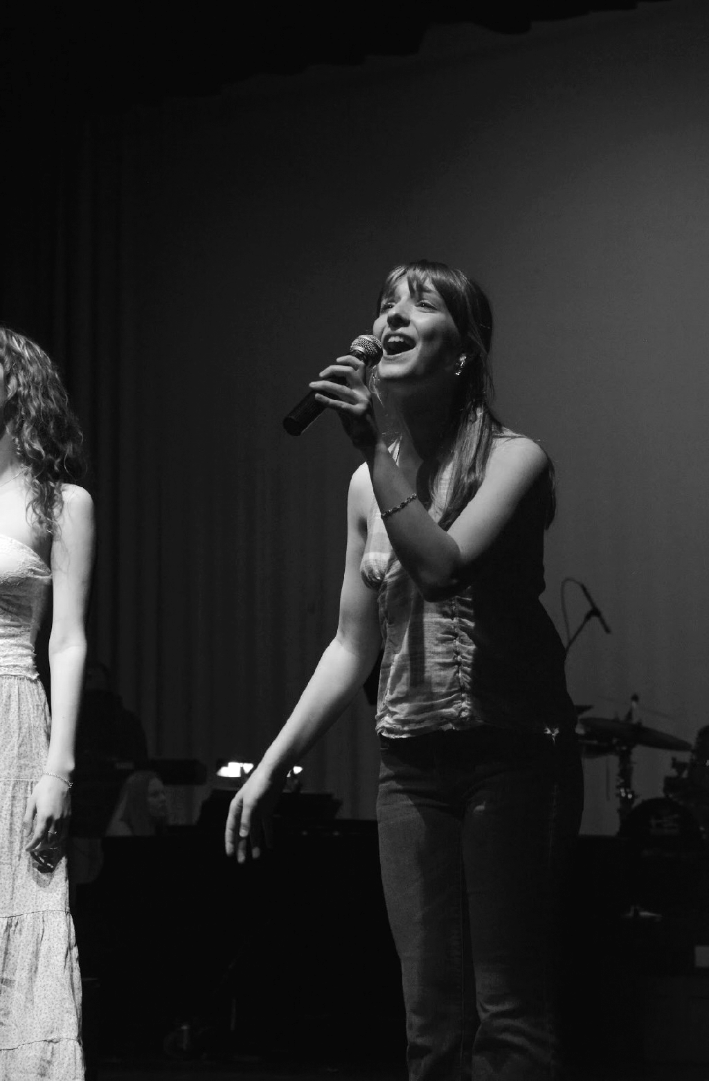A woman singing on stage holding a microphone in a black and white photograph.