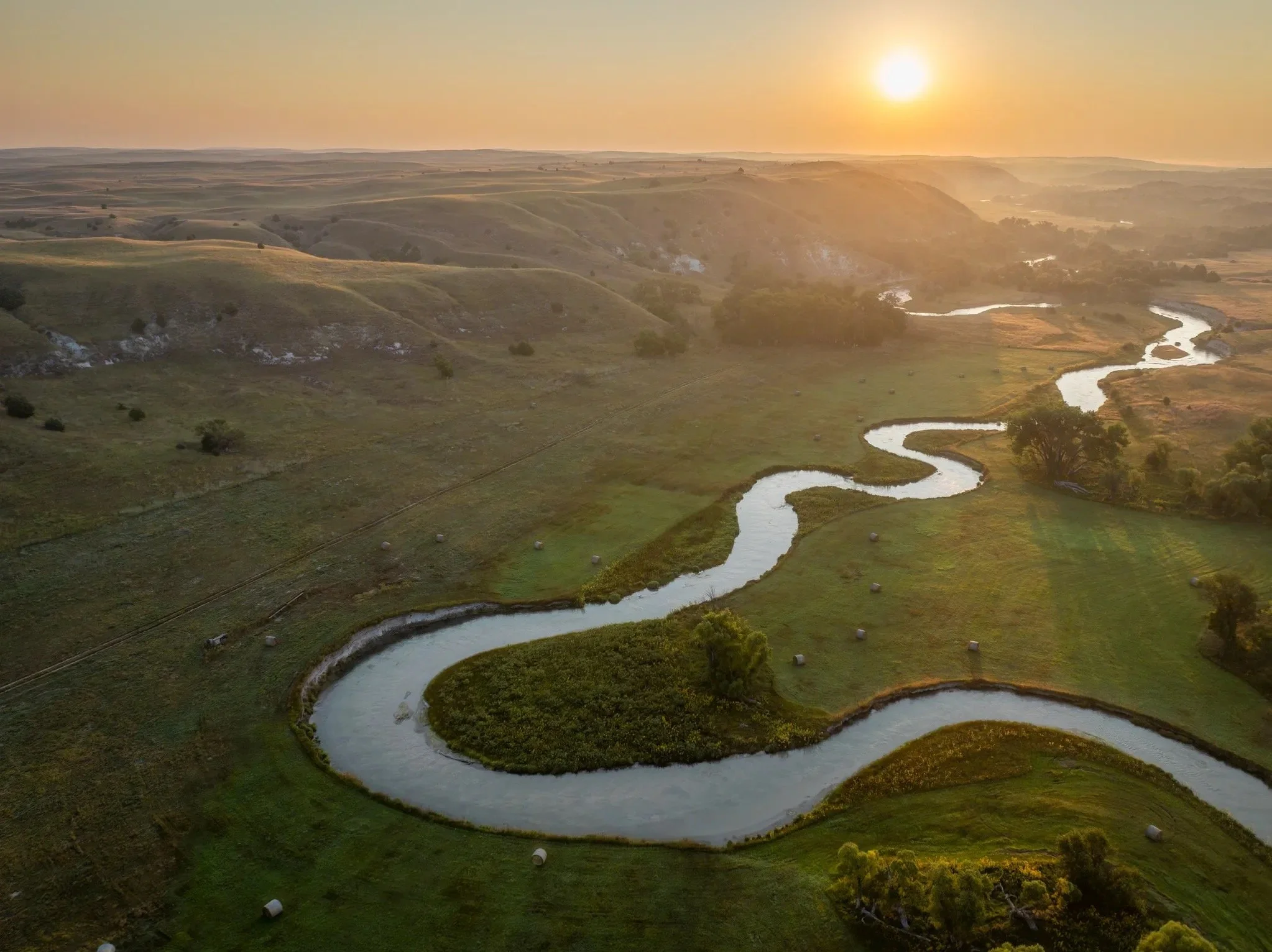 A winding river through green hills at sunrise