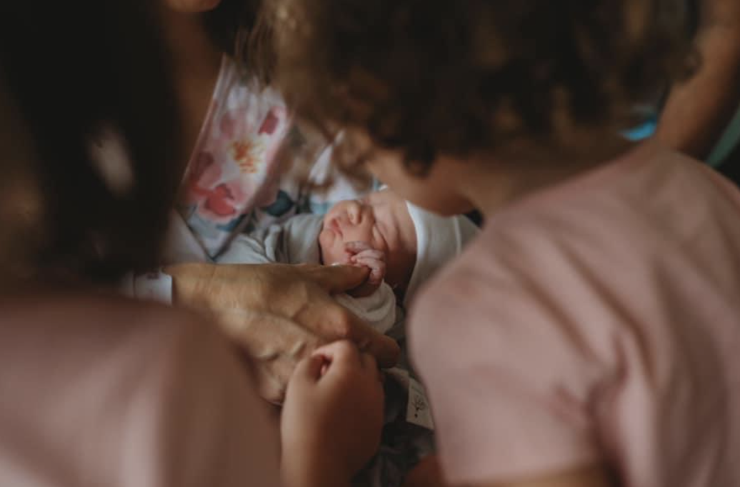 Sisters looking at their newborn sibling