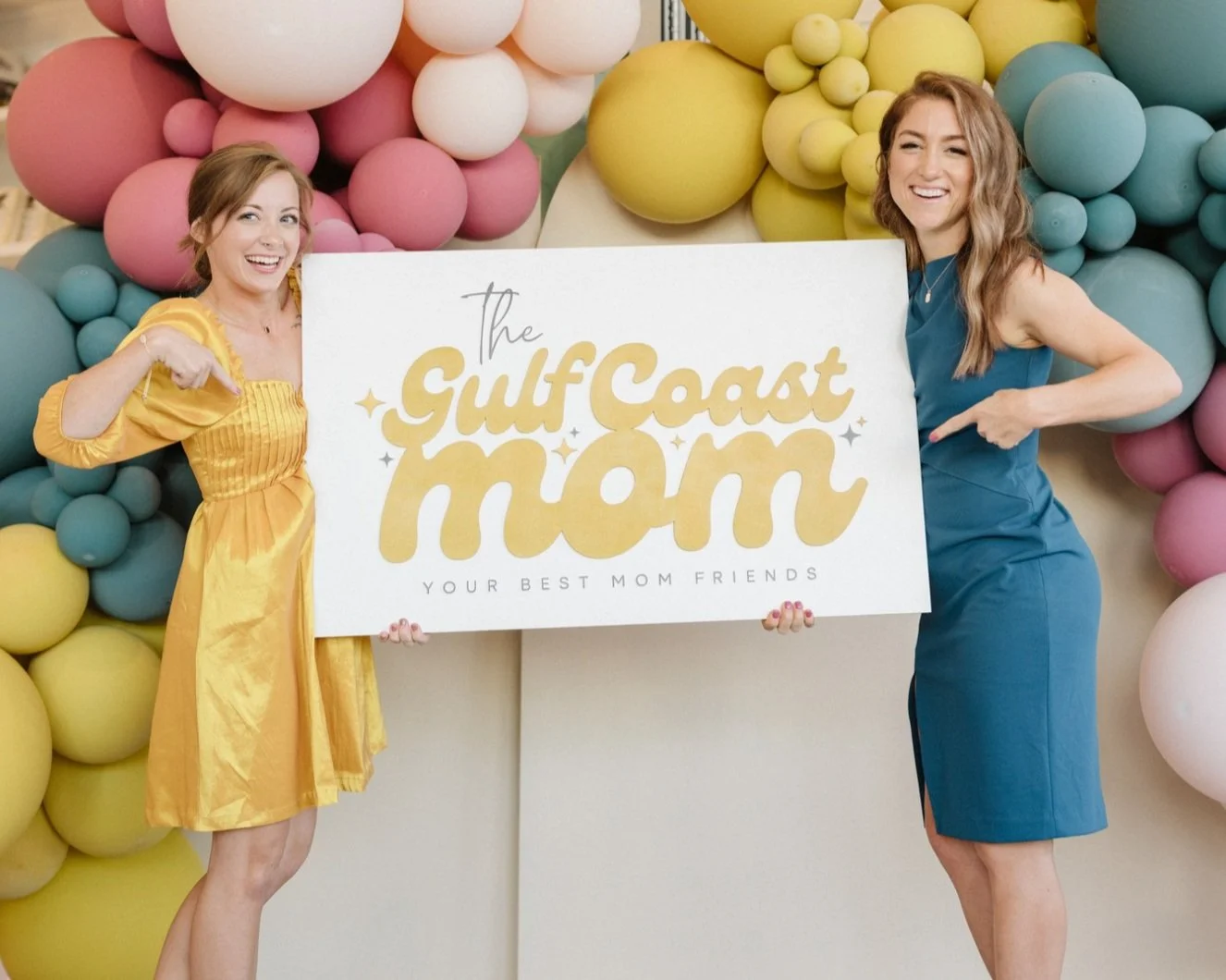 Erin and Jen holding The Gulf Coast Mom sign at their rebrand launch event