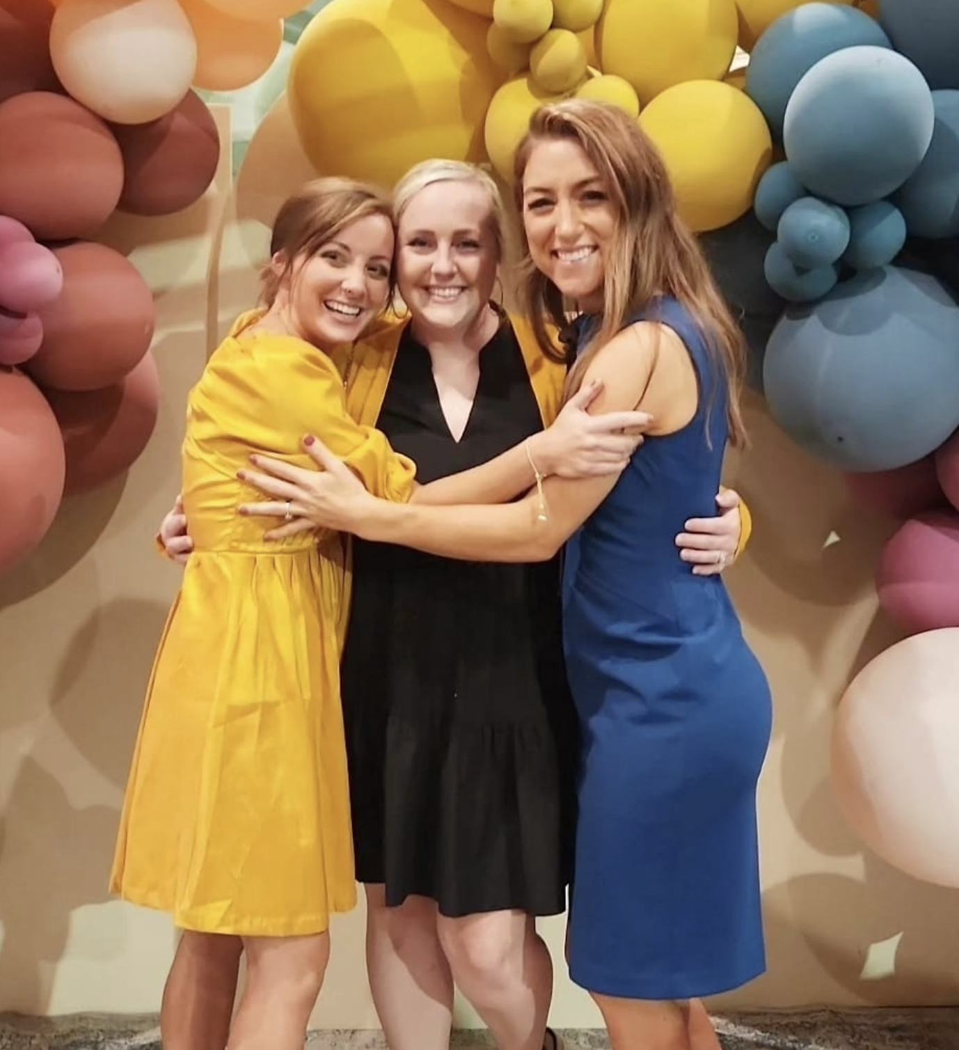 Guests hugging in front of the balloon wall at The Gulf Coast Mom launch event